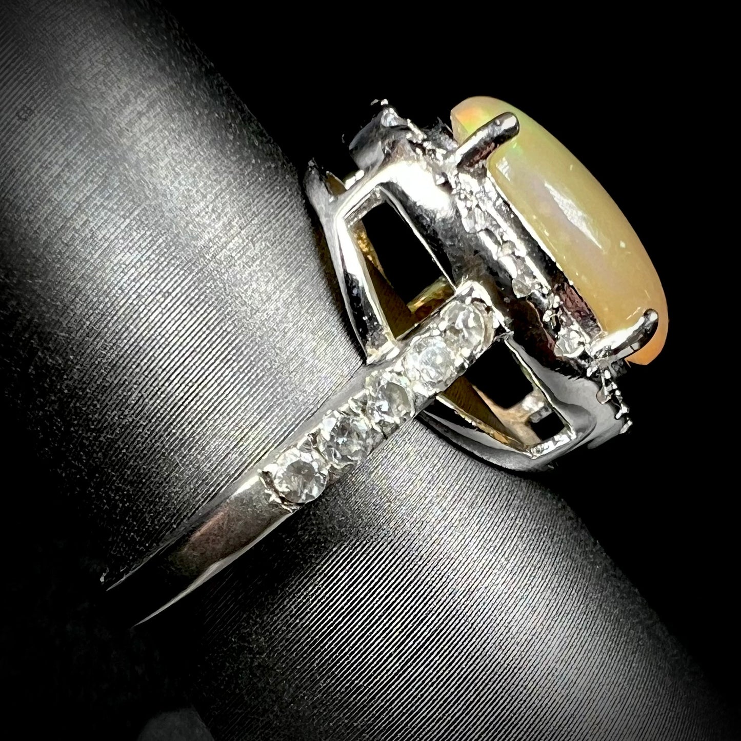 Side profile view of a sterling silver Ethiopian fire opal ring with a CZ halo.