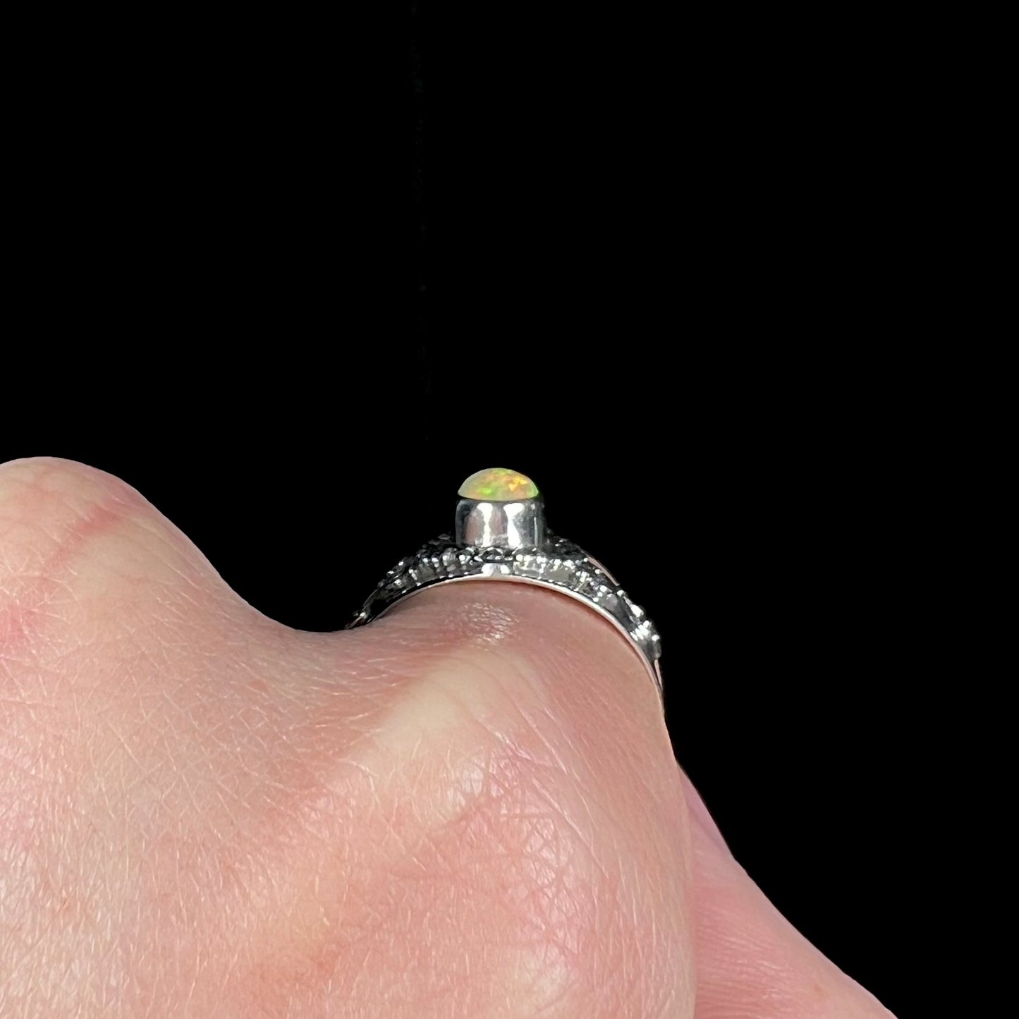 The side gallery profile of a silver Boho ring worn on a finger, showing the ring's silver bezel.