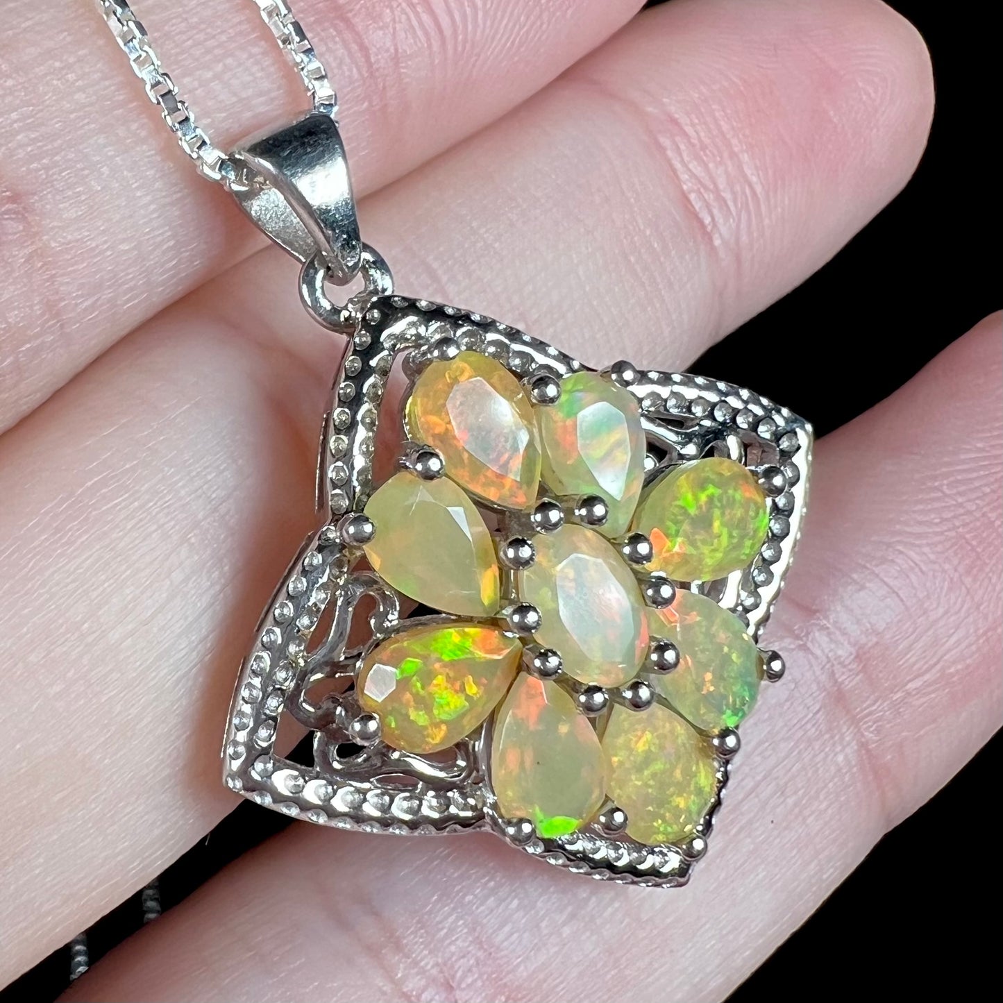 A sterling silver Ethiopian opal necklace shown at an angled view, held in a hand.