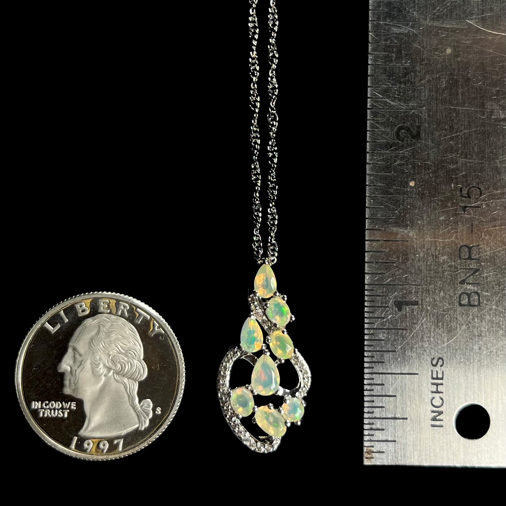 A sterling silver Ethiopian opal and cubic zirconia necklace, shown next to a quarter coin and ruler.
