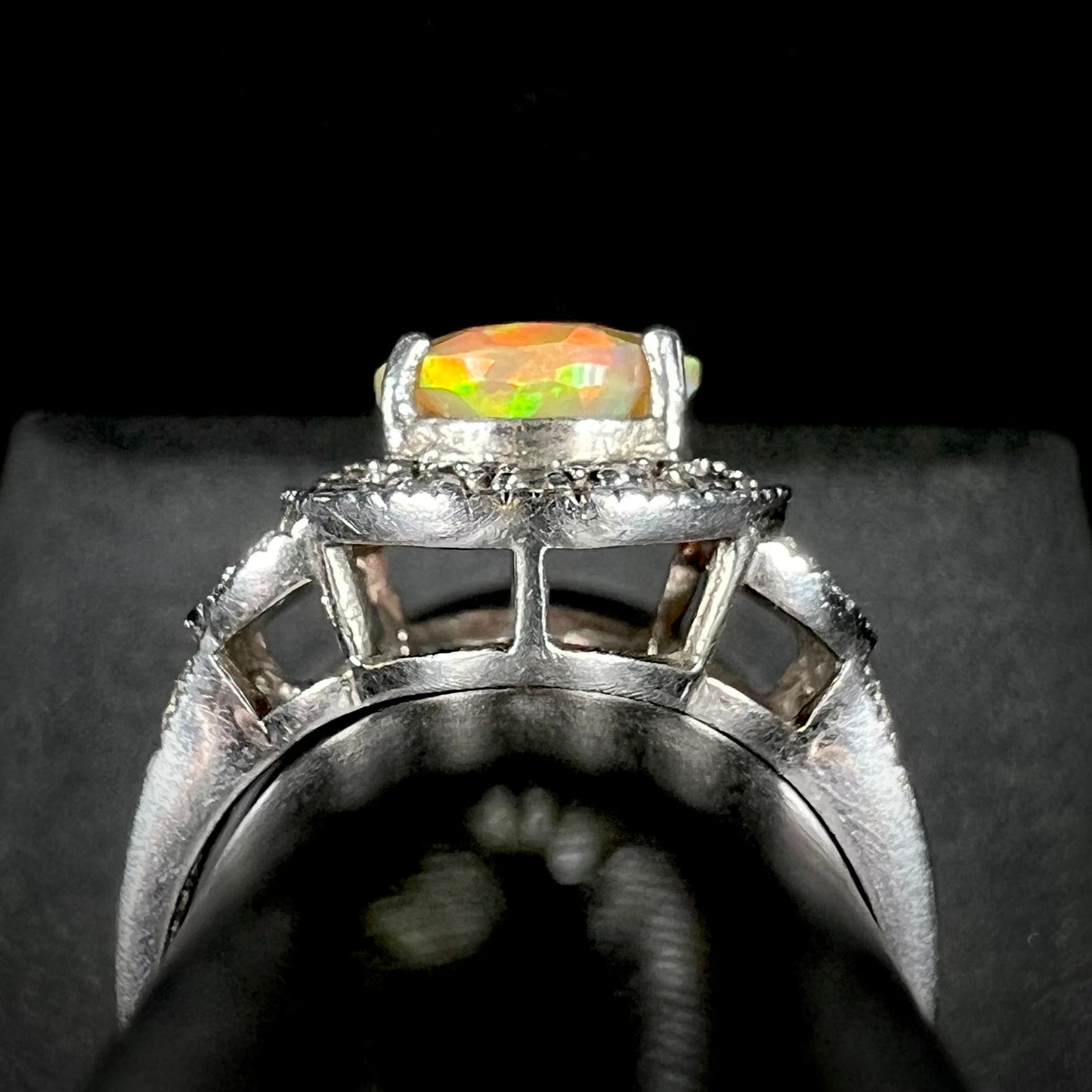 Side gallery profile view of a silver ring set with an Ethiopian opal against a black and gray background.