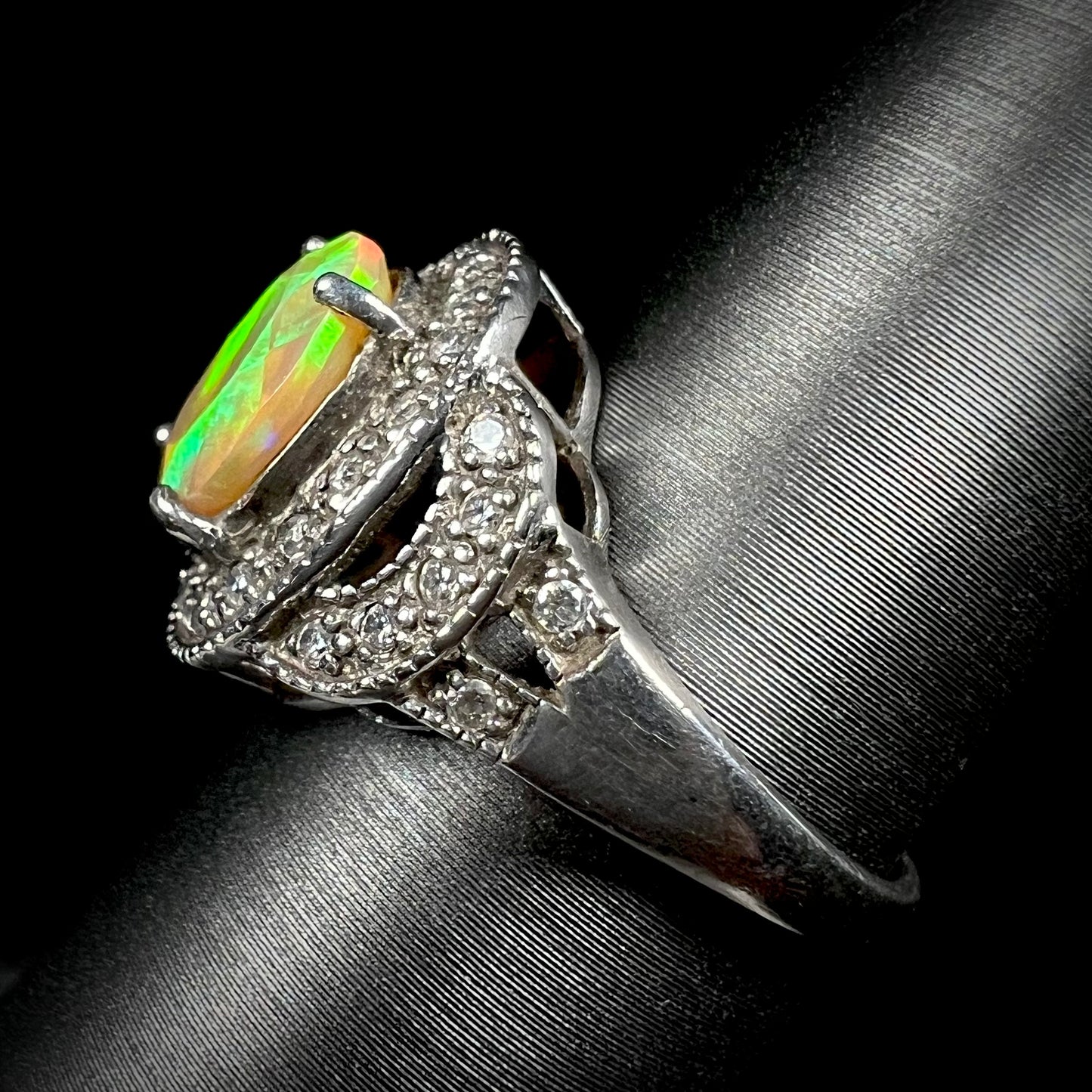 Side view of silver ring set with green Ethiopian opal and cubic zirconia accents against a black background.