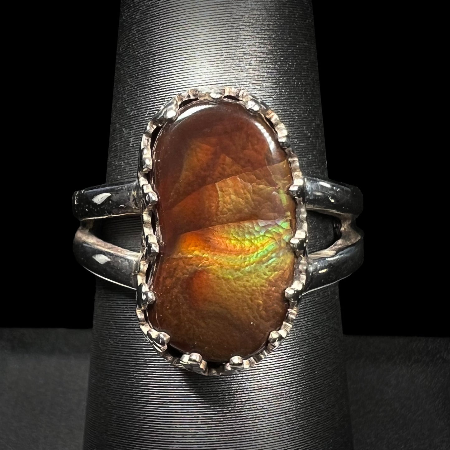 Sterling silver Mexican fire agate ring with a split shank shown from the front view against a black background.