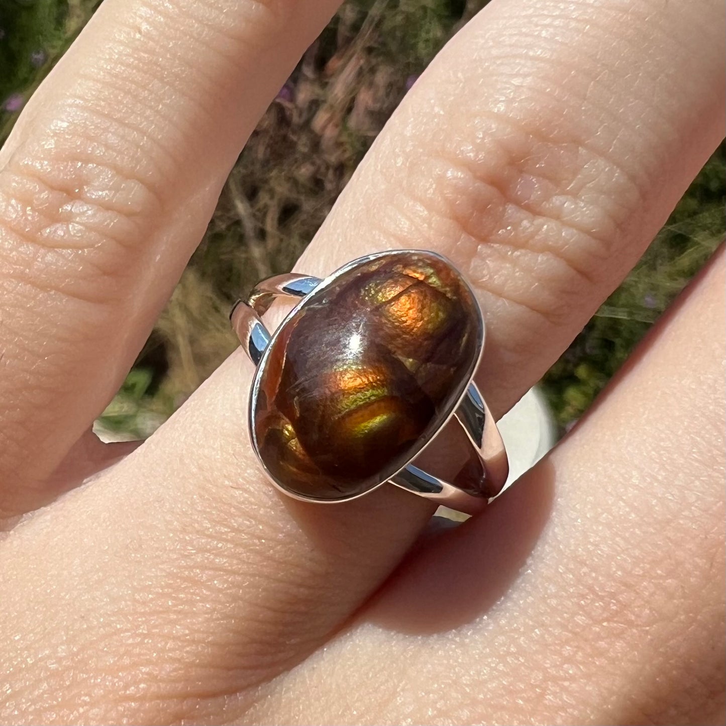 Close-up front view of a sterling silver Mexican fire agate ring with a split shank in the sunlight.