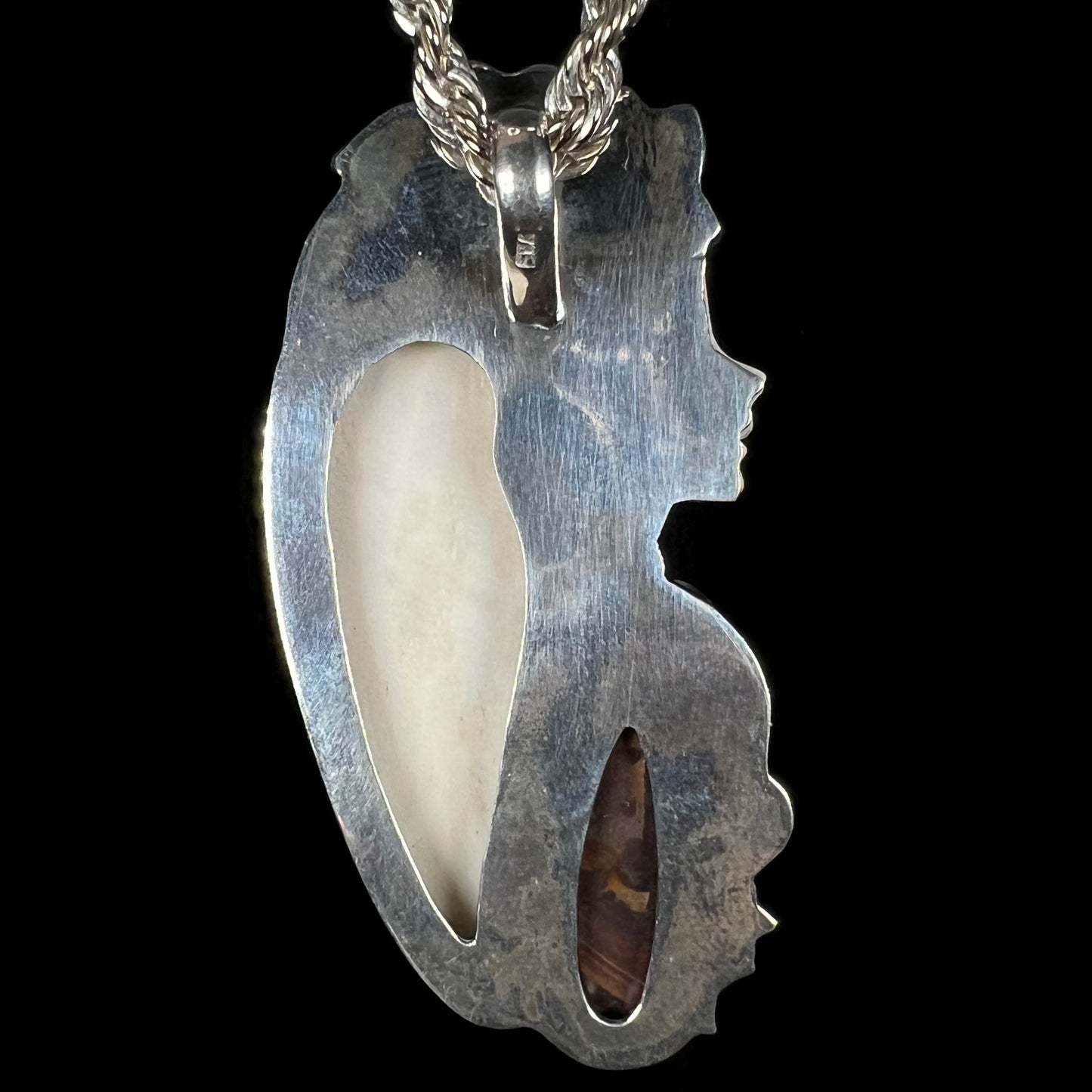 Back view of a sterling silver goddess pendant against a black background.