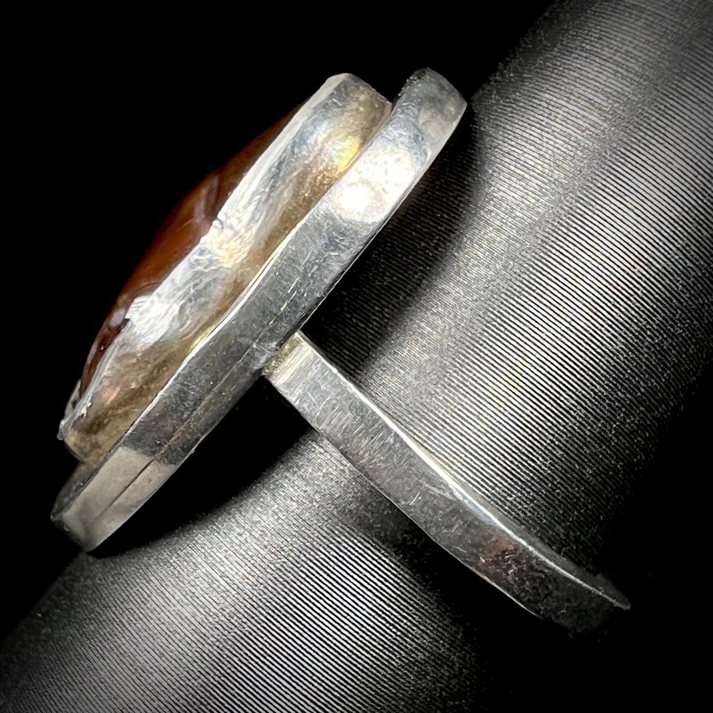 A handmade sterling silver fire agate ring shown from the side view, focusing on the silver shank.