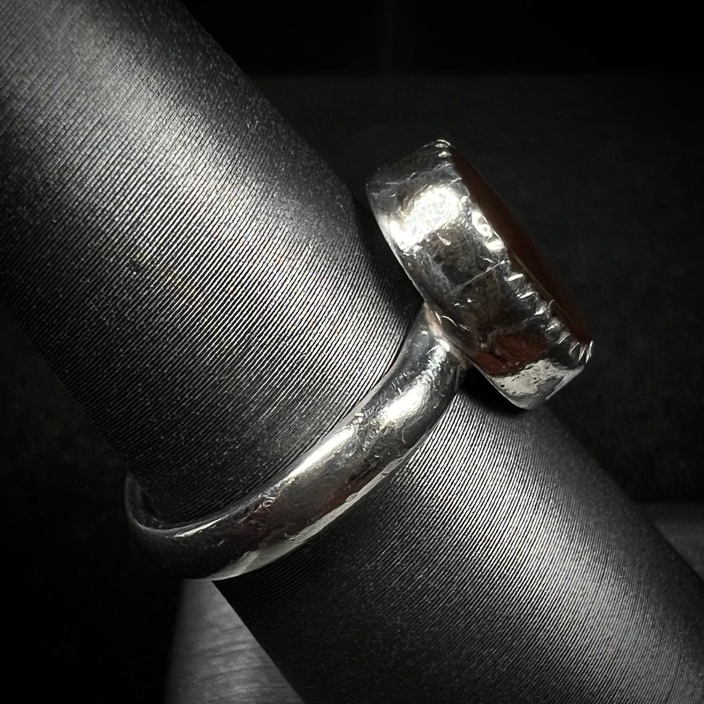 A sterling silver ladies' solitaire ring shown from the side. The ring's shank shows signs of wear.
