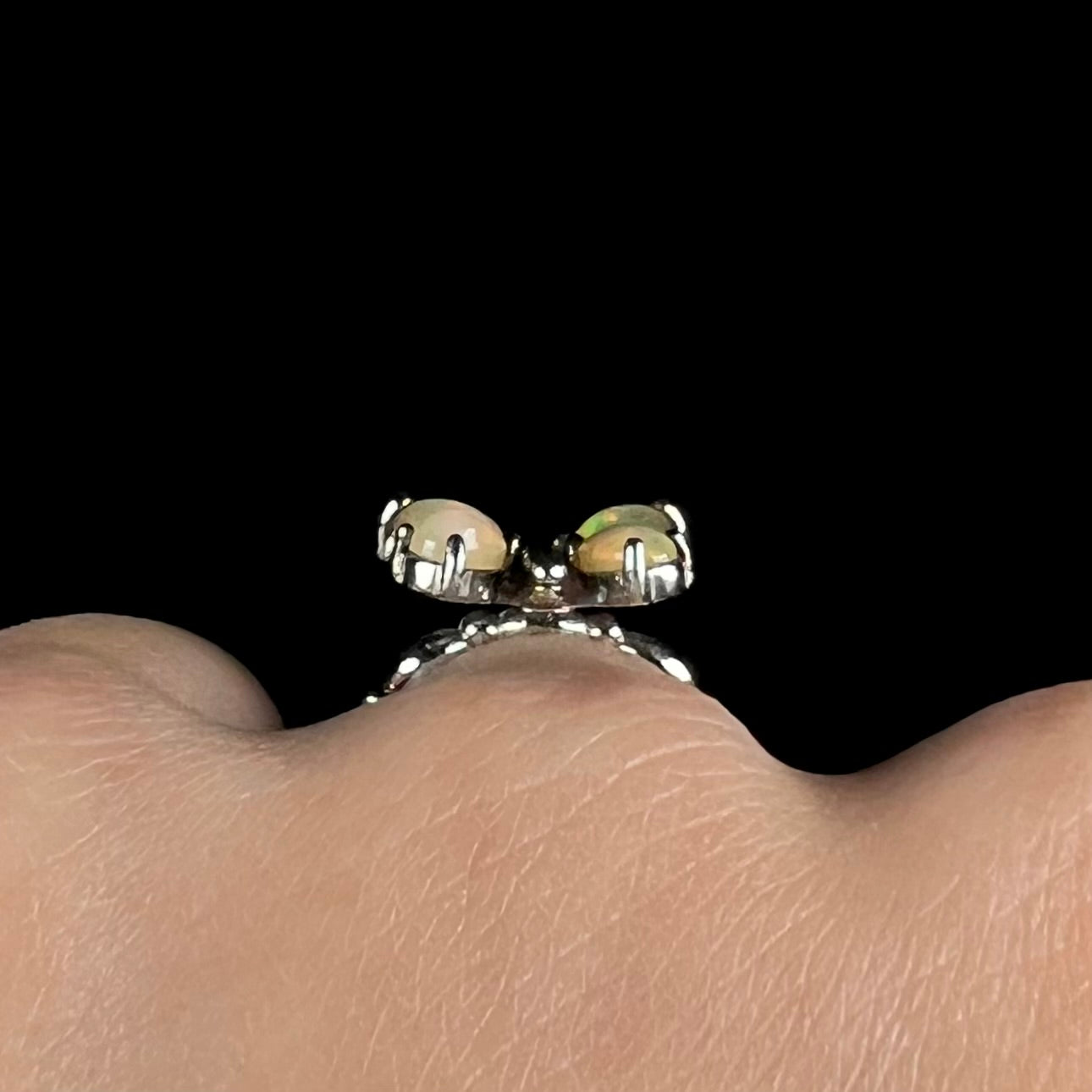 Close-up gallery view of a sterling silver Ethiopian opal butterfly ring worn on a finger.