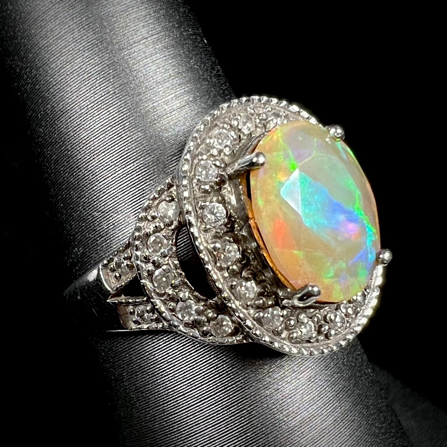 A silver opal ring with a CZ halo shown at an angled view. The Ethiopian opal shows blue color play.