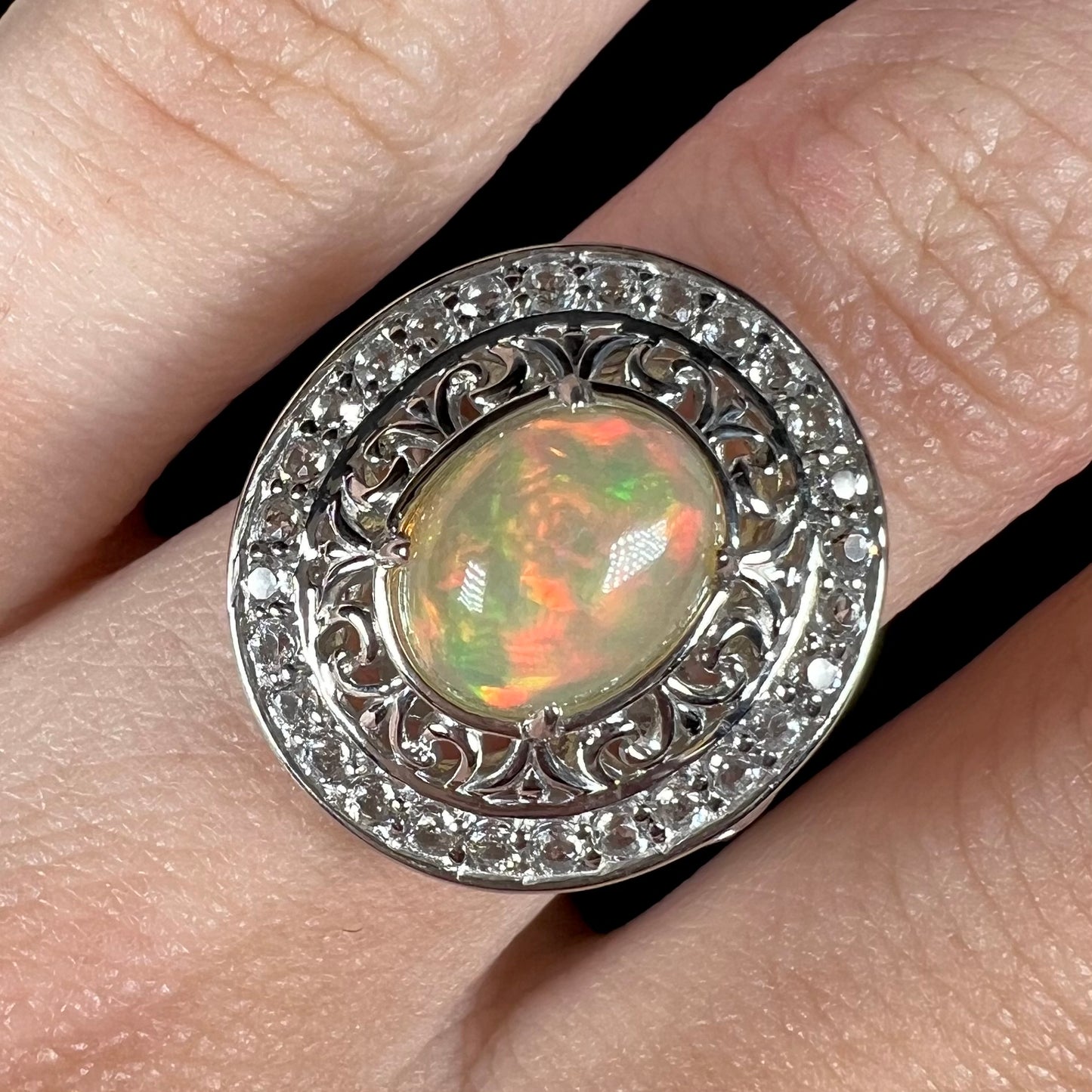 A sterling silver Ethiopian opal halo ring with a double halo of filigree and white topaz accents.