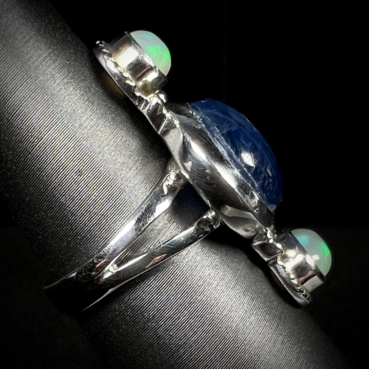 Side view of silver split shank opal kyanite ring against black backdrop. The stones are not in clear view.