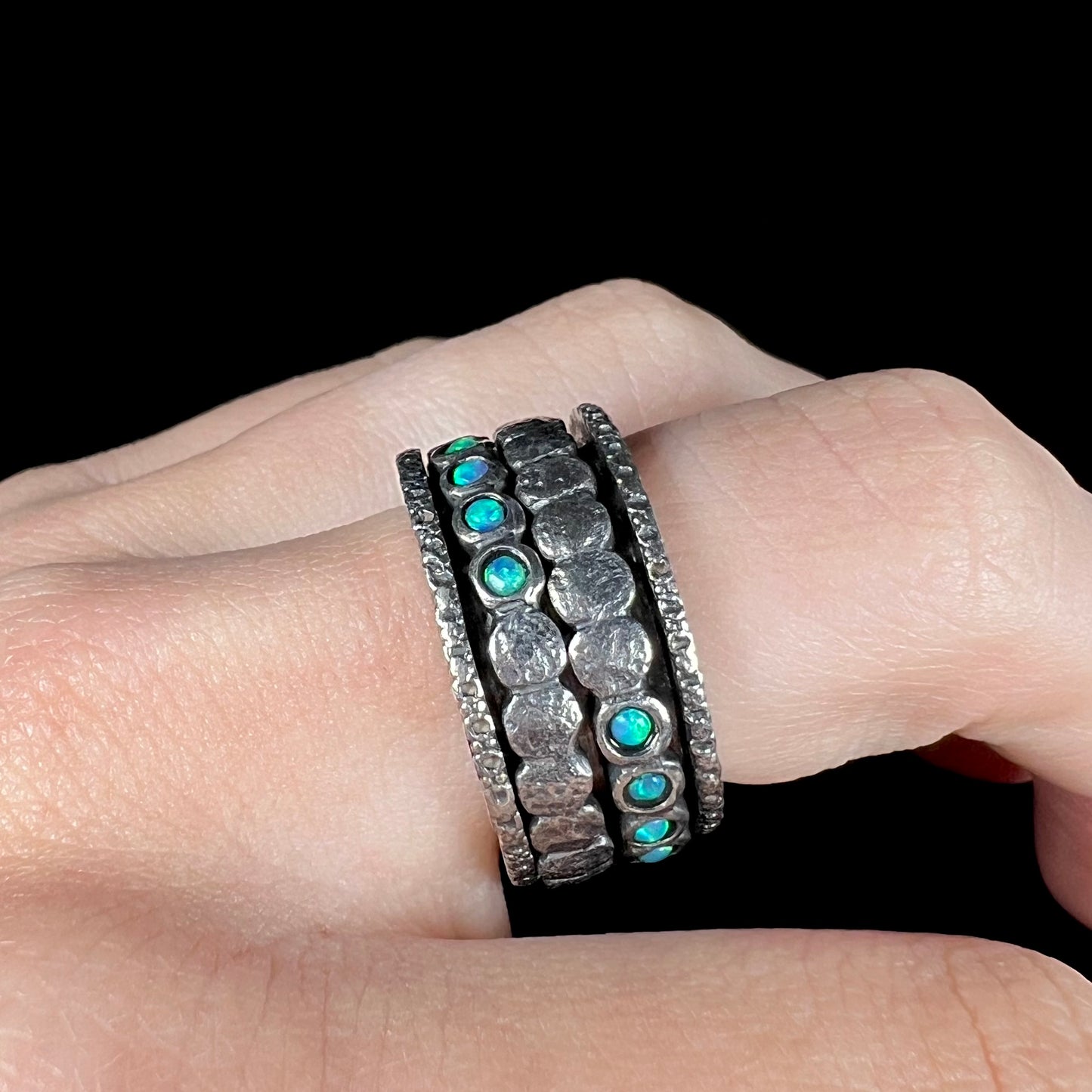 A sterling silver opal men's ring worn on a finger. The ring is an 11.5mm wide band with two spinning rings inside.