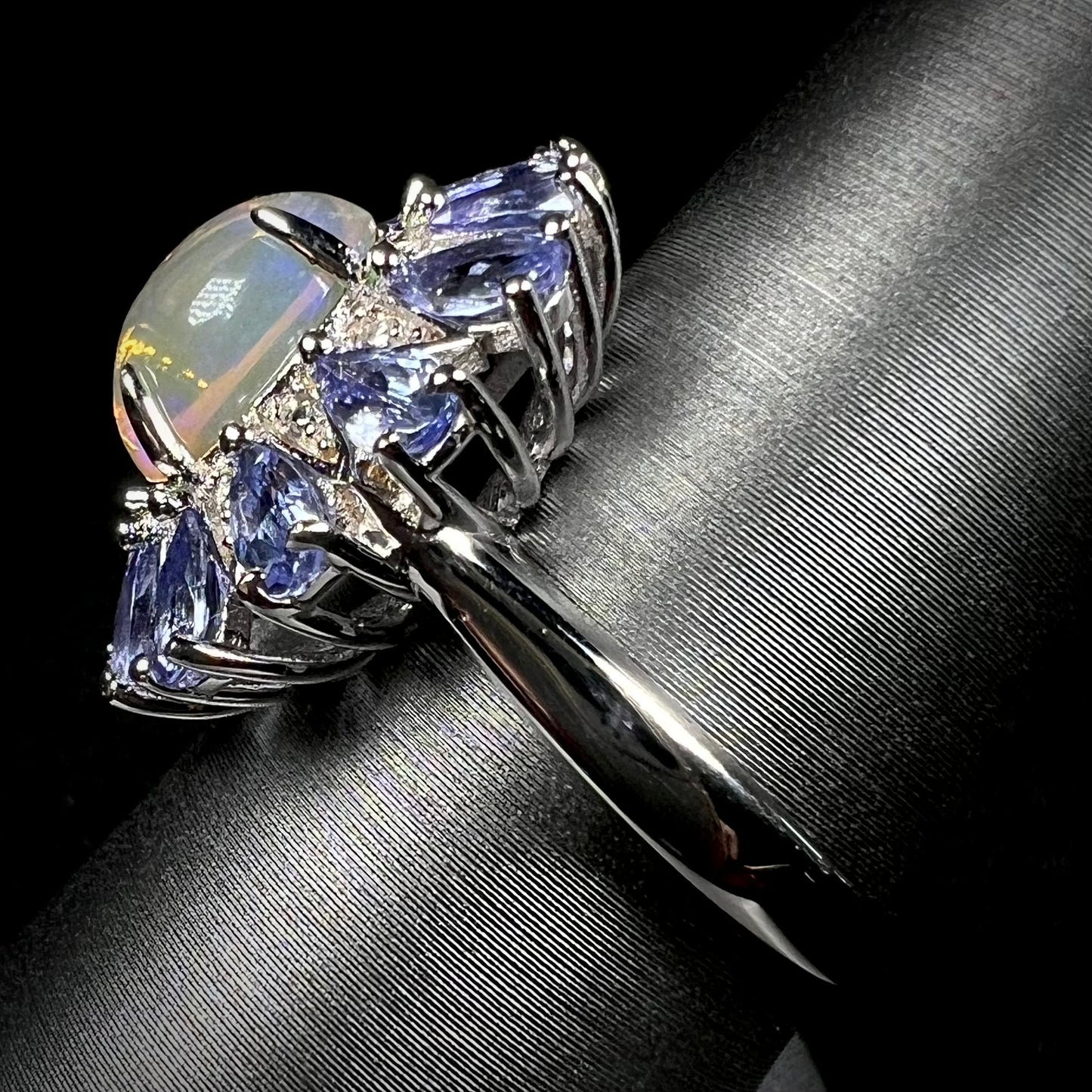 Side view of a silver opal tanzanite ring. The ring's shank is in view.