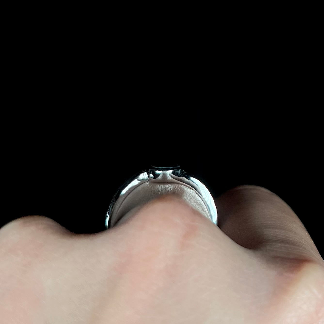 A sterling silver ring bezel-set with an oval shaped black opal doublet. The opal has red and blue fire.