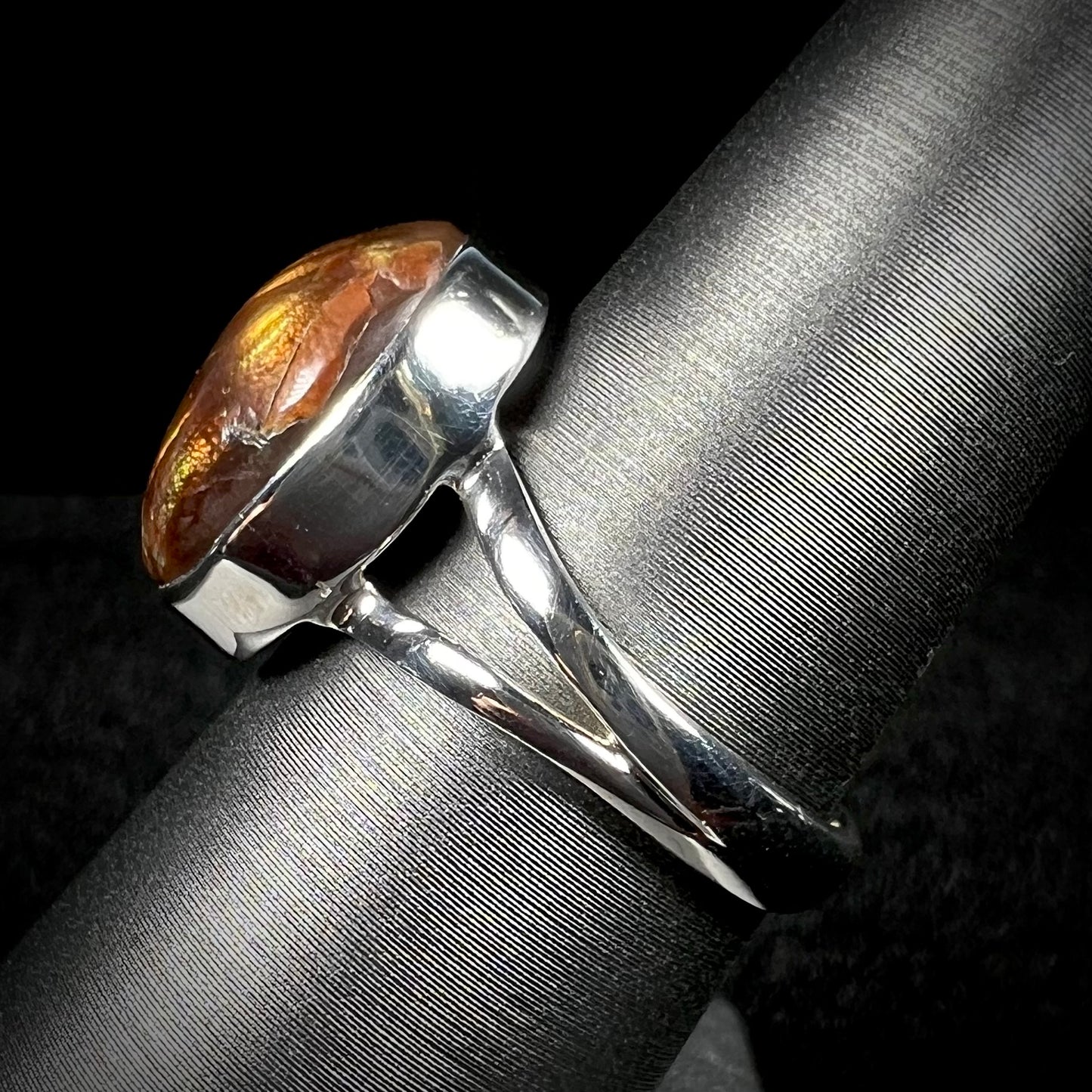 Side view of silver split shank fire agate ring against dark background.