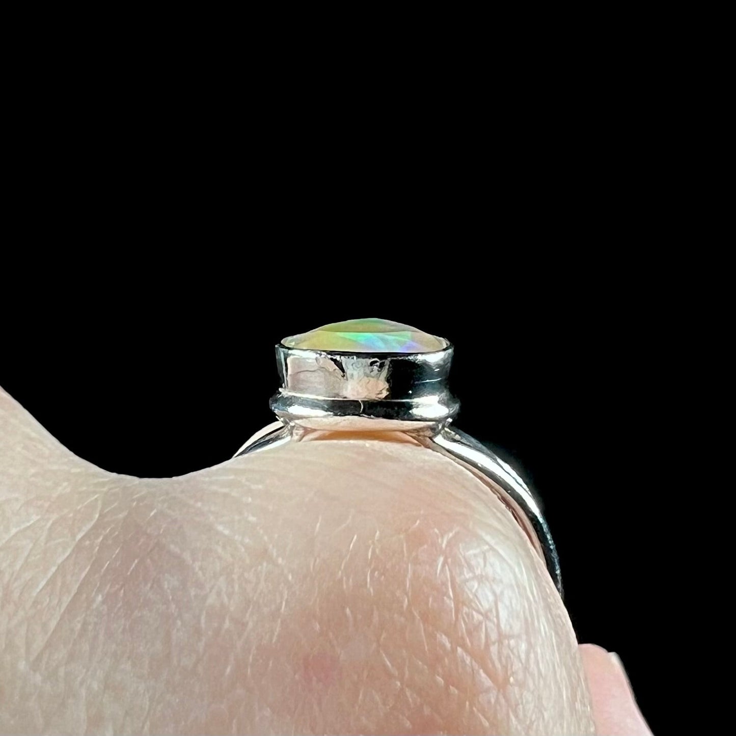 A unisex sterling silver ring set with a faceted pear shaped Ethiopian fire opal. The opal plays orange, red, and green colors.