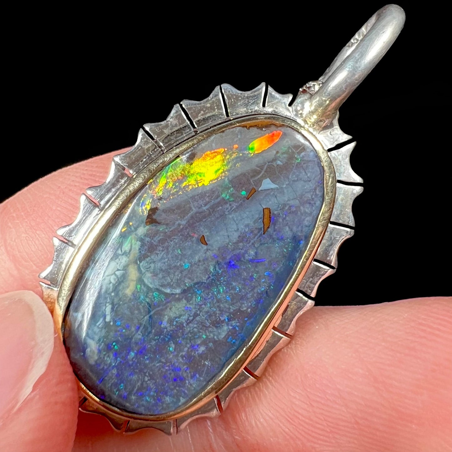 A Southwest style two-tone sterling silver pendant set with a black boulder opal with a yellow gold bezel.