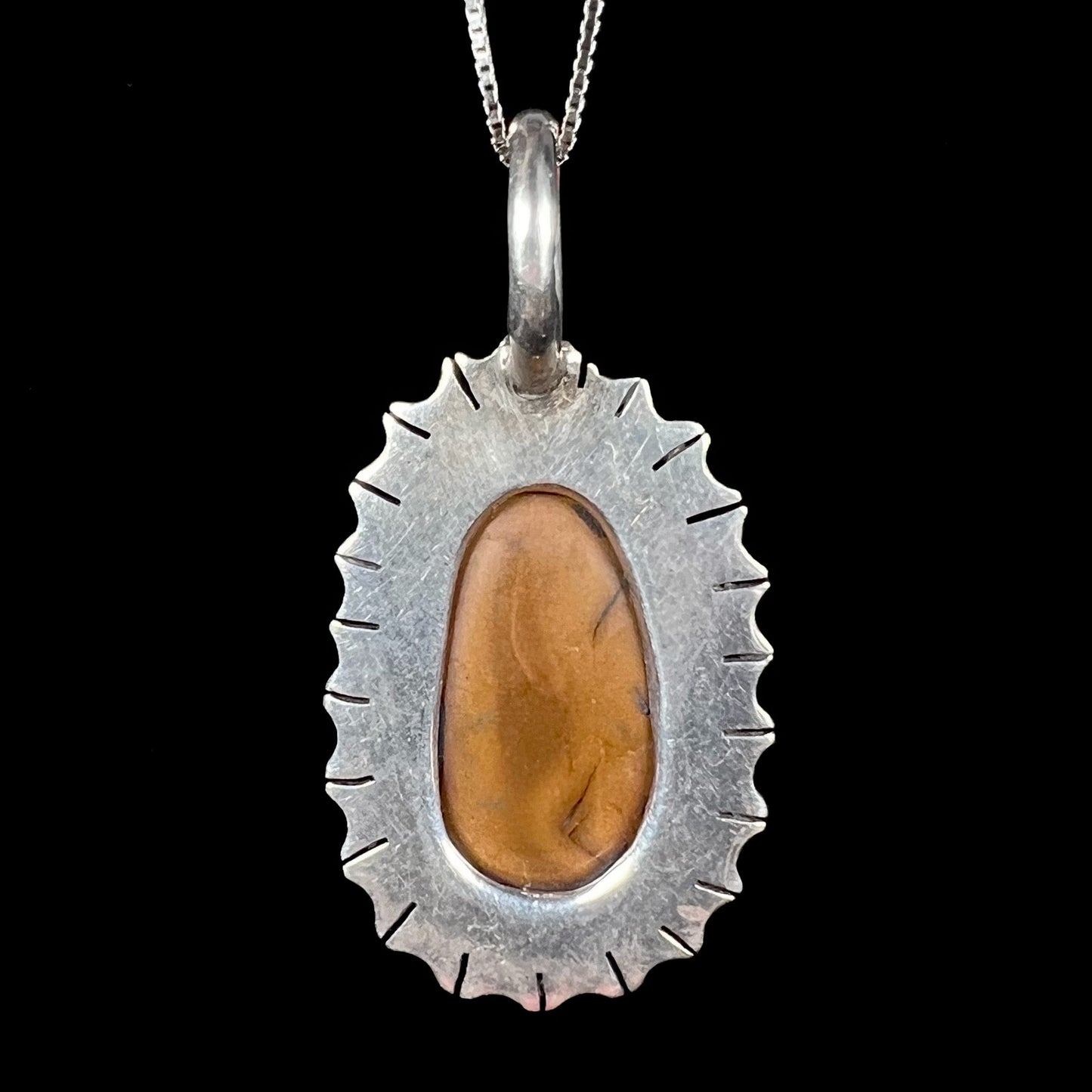 A Southwest style two-tone sterling silver pendant set with a black boulder opal with a yellow gold bezel.