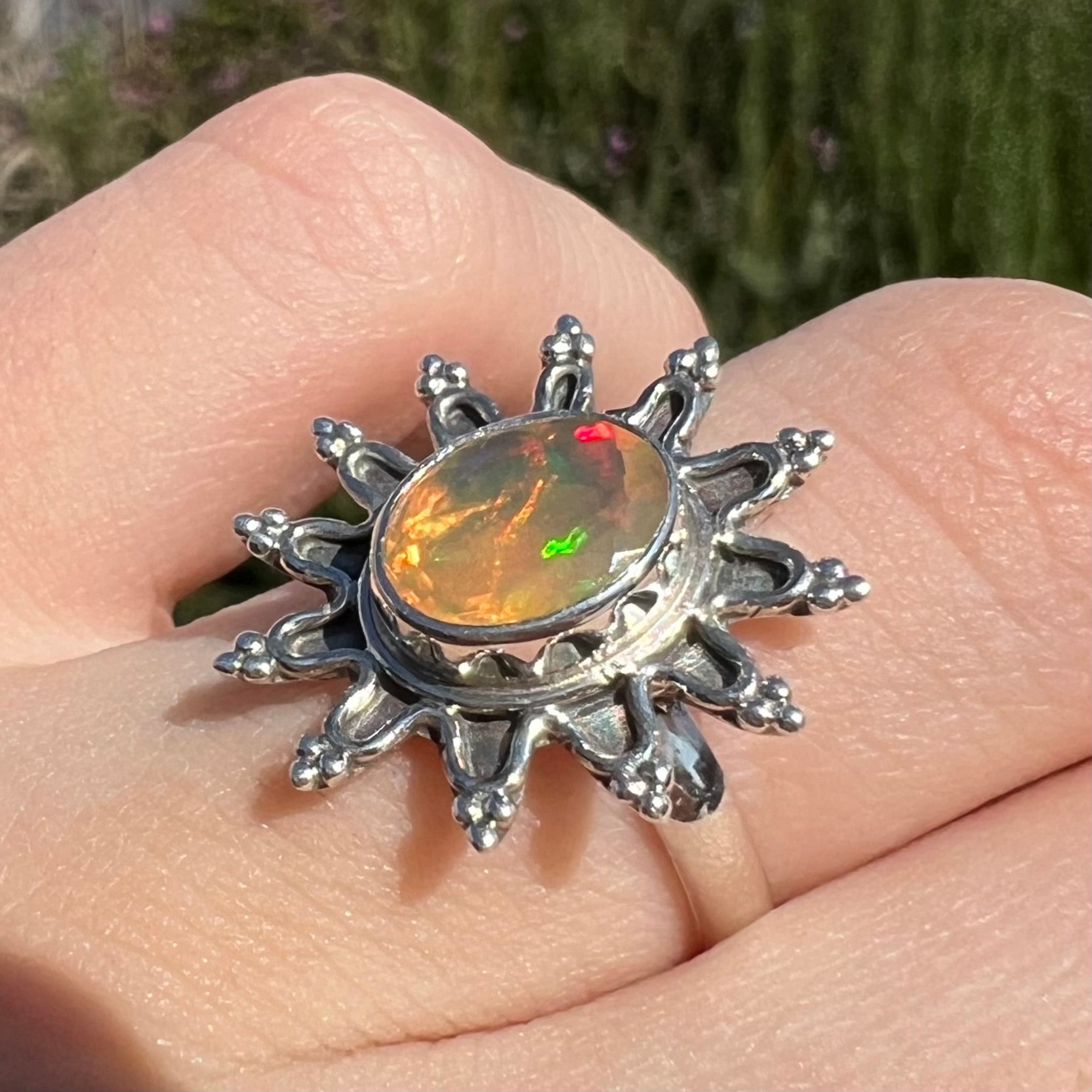 A sterling silver sunburst-style ring mounted with a faceted oval cut Ethiopian fire opal.