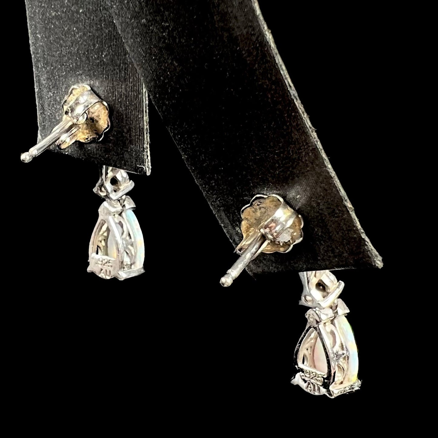 A pair of sterling silver filigree dangle earrings mounted with pear shaped lab created opals and diamond accents.