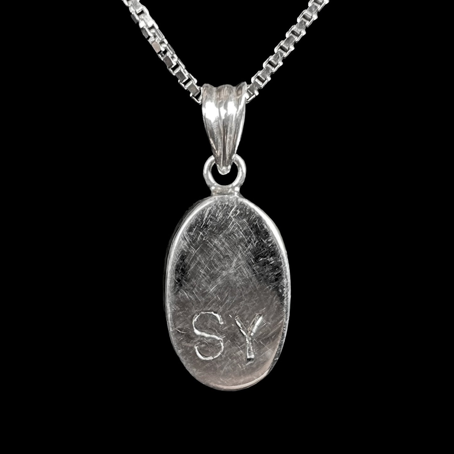 A ladies' sterling silver necklace bezel set with a natural white crystal opal. The opal has red and blue fire.