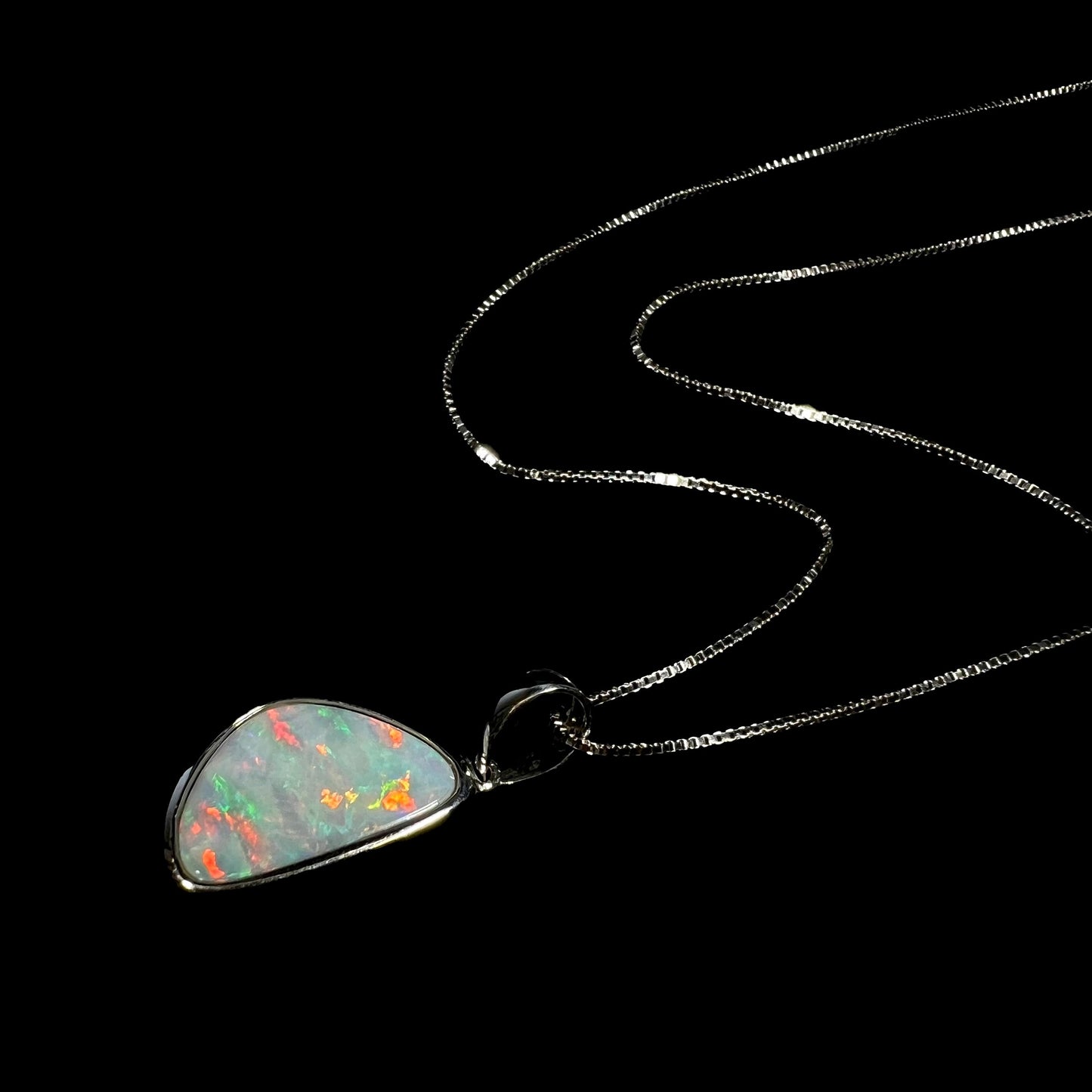 A sterling silver pendant bezel set with a white Australian crystal opal on a box chain.