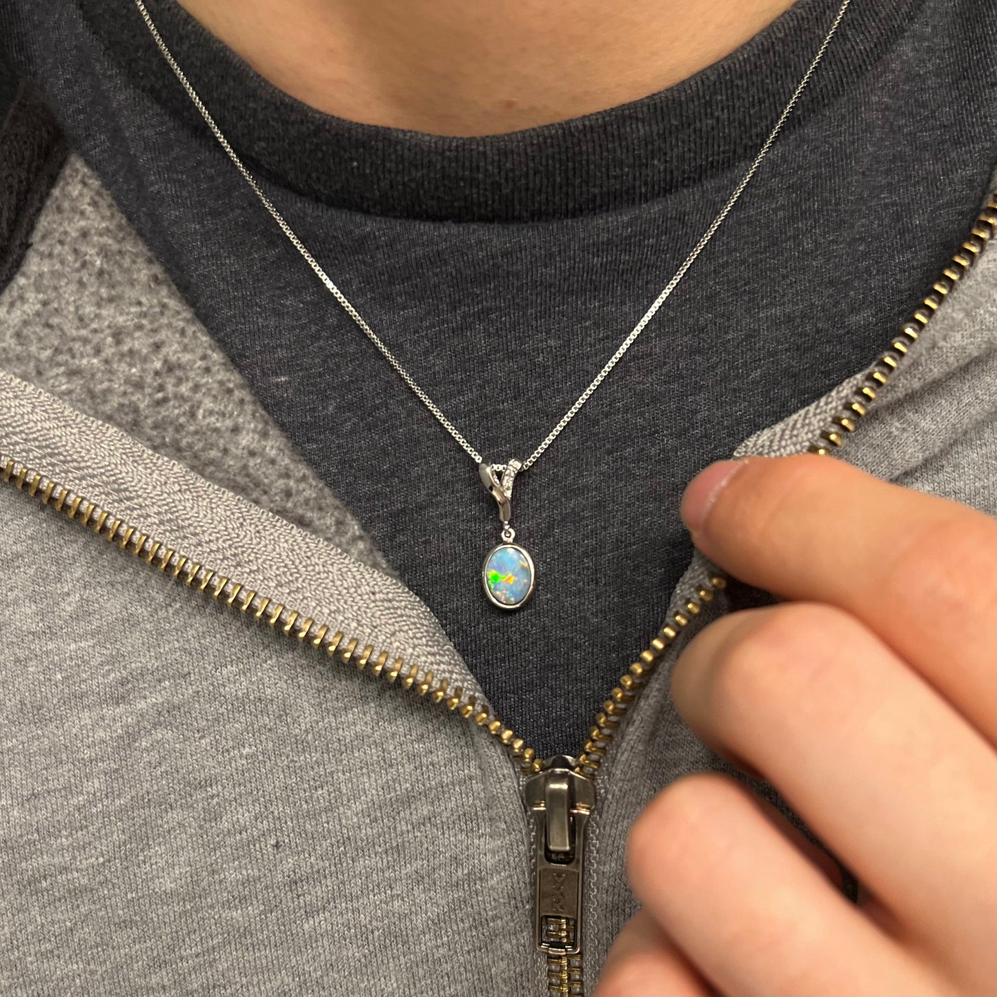A sterling silver necklace set with a natural black opal doublet and white zircon accent stones.
