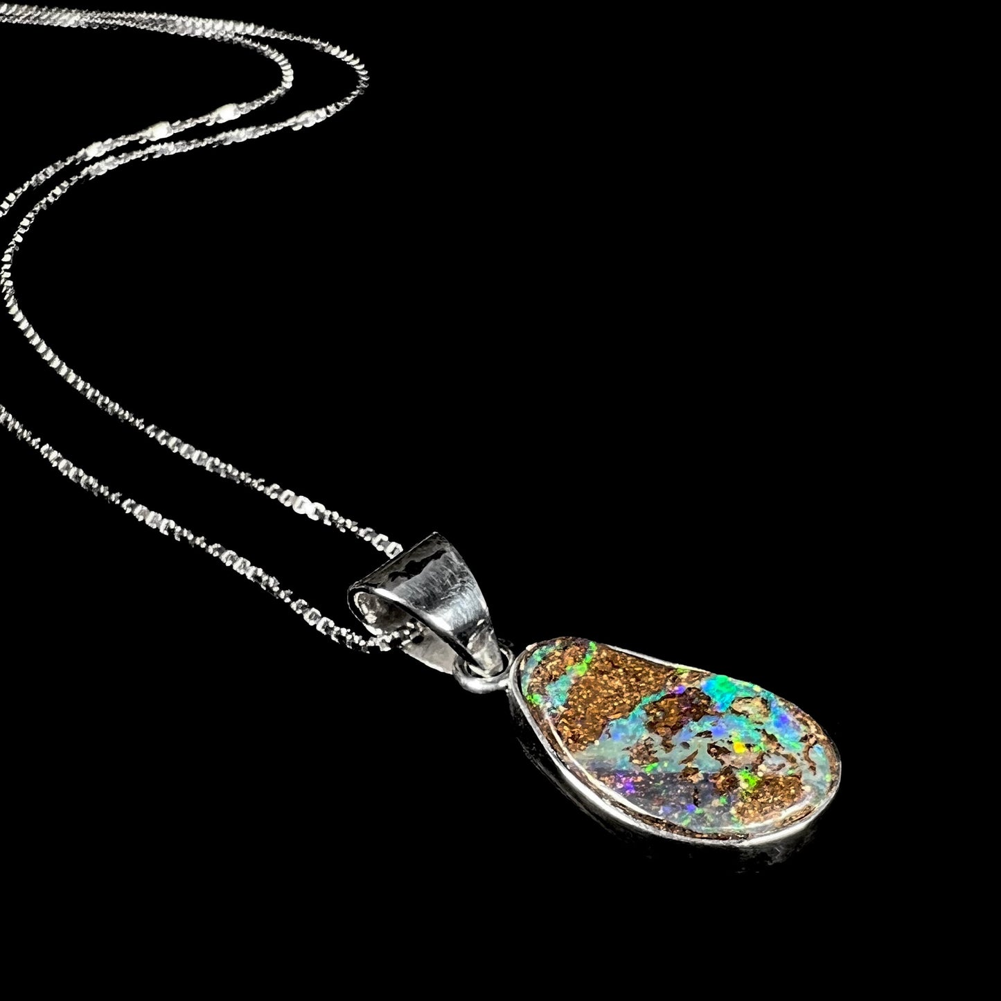 A sterling silver pendant set with an Australian boulder opal on a silver box chain.