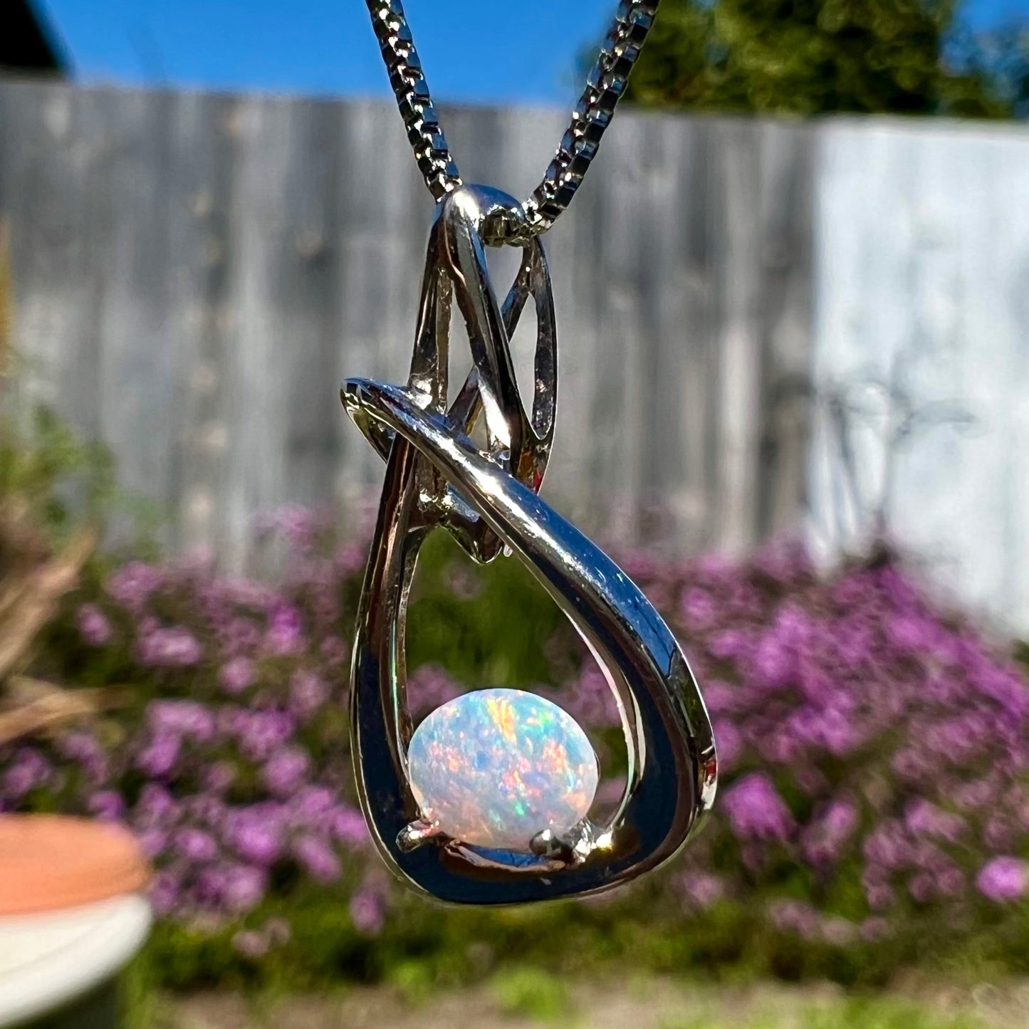 A ladies' sterling silver pendant set with an oval cabochon cut natural white crystal opal.
