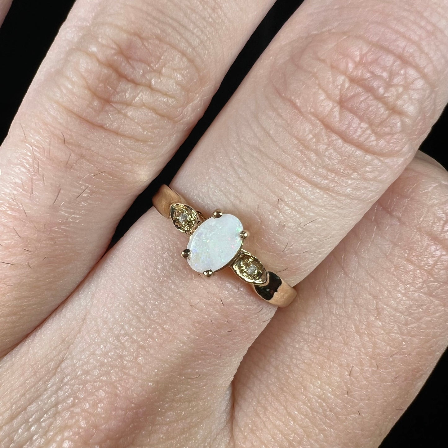 A dainty ladies' yellow gold opal and diamond ring. The opal has subtle play of color.