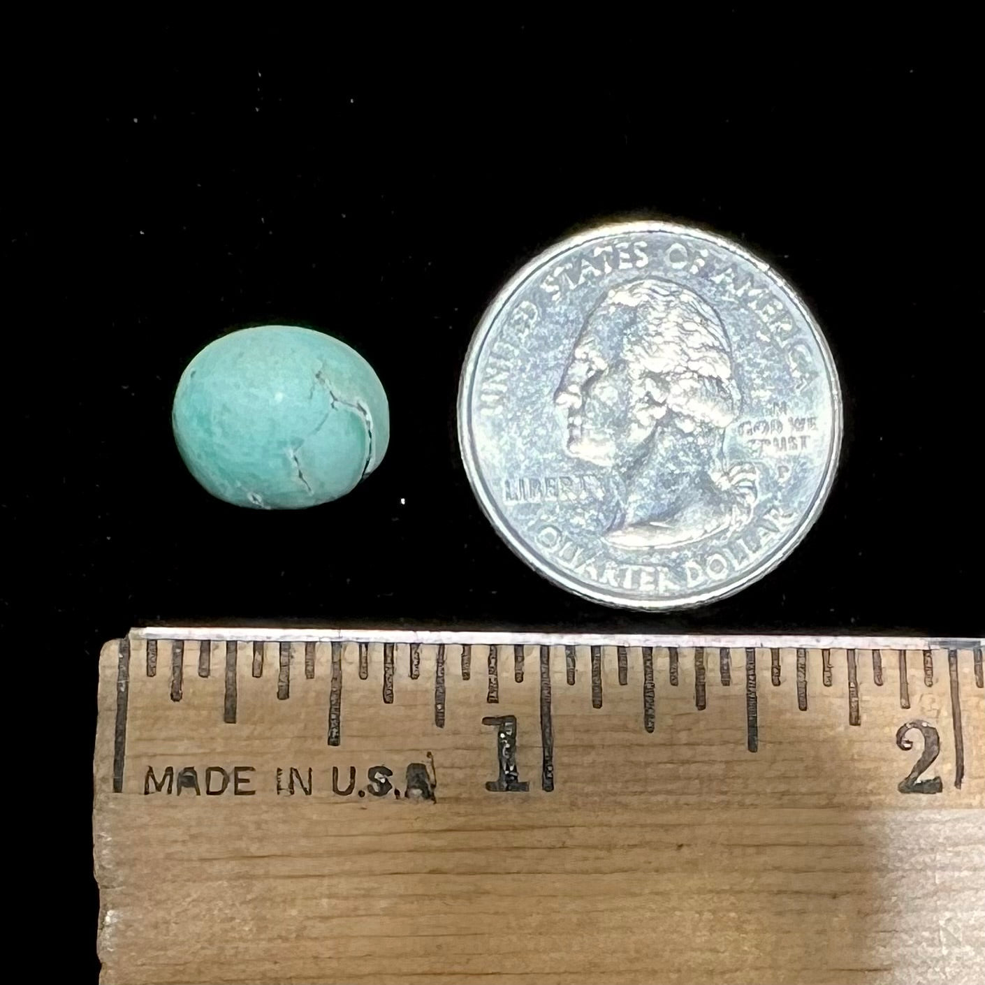 A loose, oval cabochon cut turquoise stone from the Sleeping Beauty Mine in Arizona. The stone is a greenish blue color.