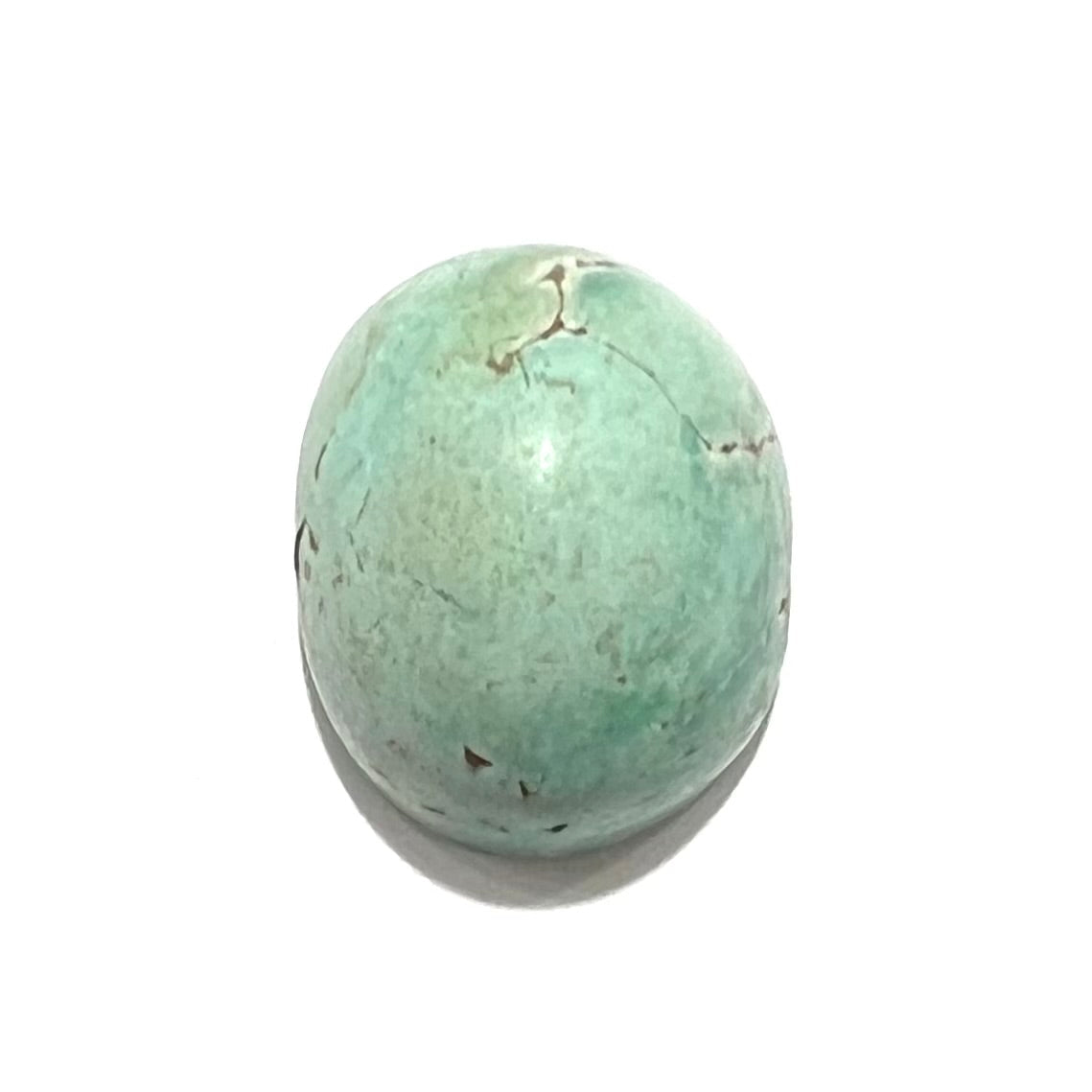A loose, oval cabochon cut turquoise stone from the Sleeping Beauty Mine in Arizona. The stone is a greenish blue color.