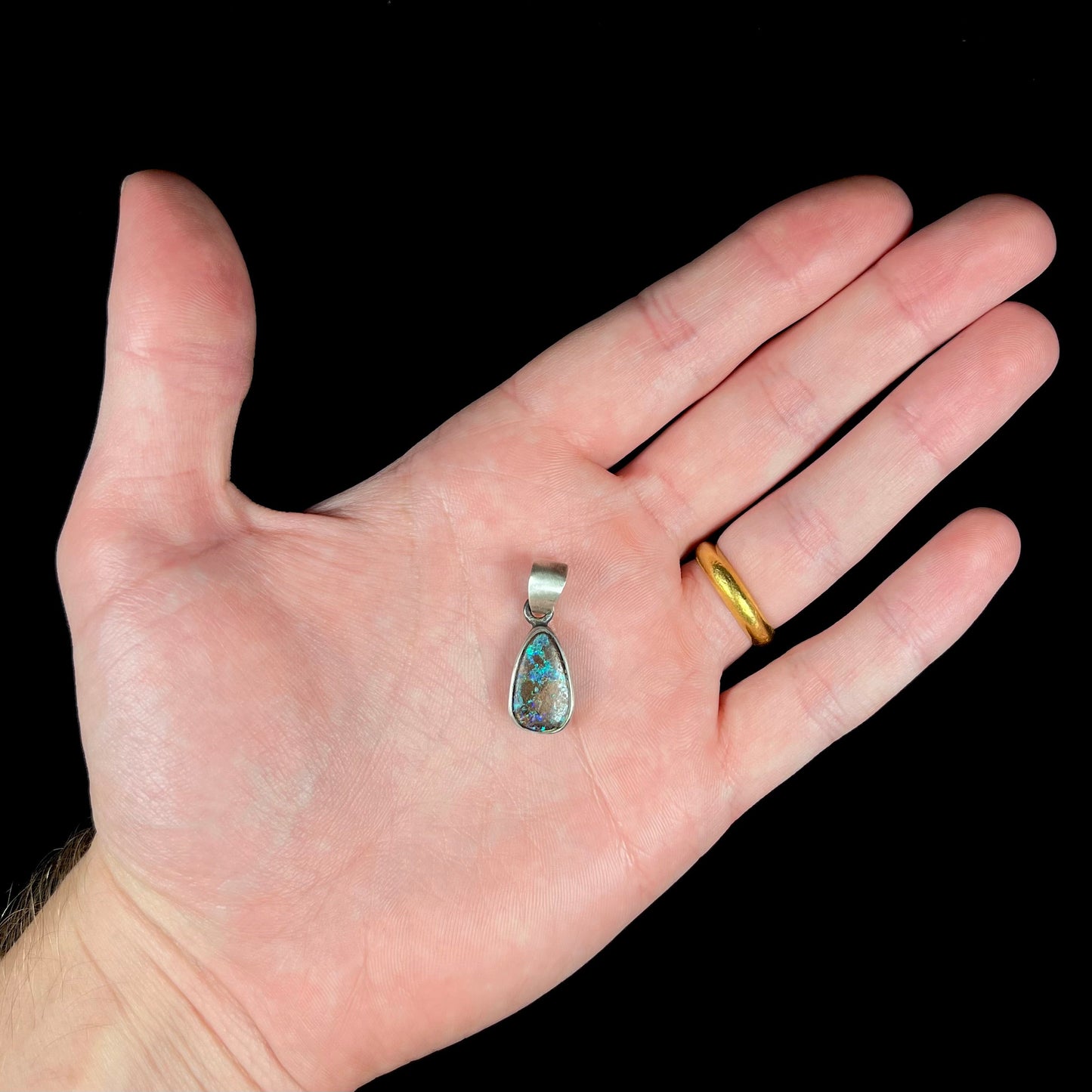 A handmade, satin finish sterling silver pendant set with a drop shaped boulder opal stone.