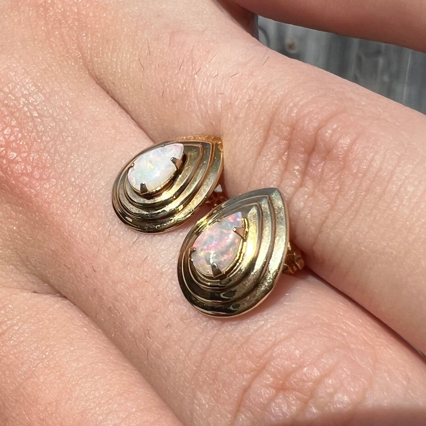 A pair of pear shaped natural opals mounted in yellow gold pushback stud earrings.