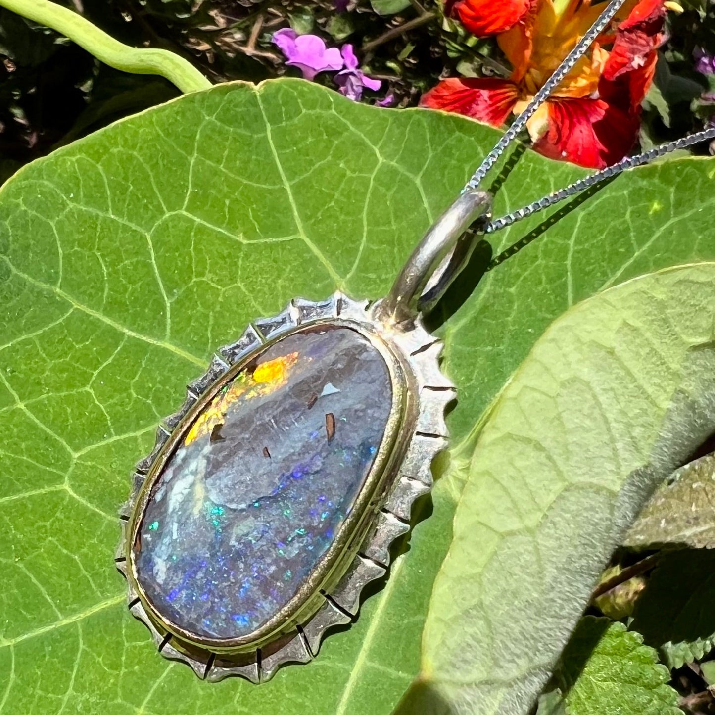 A Southwest style two-tone sterling silver pendant set with a black boulder opal with a yellow gold bezel.