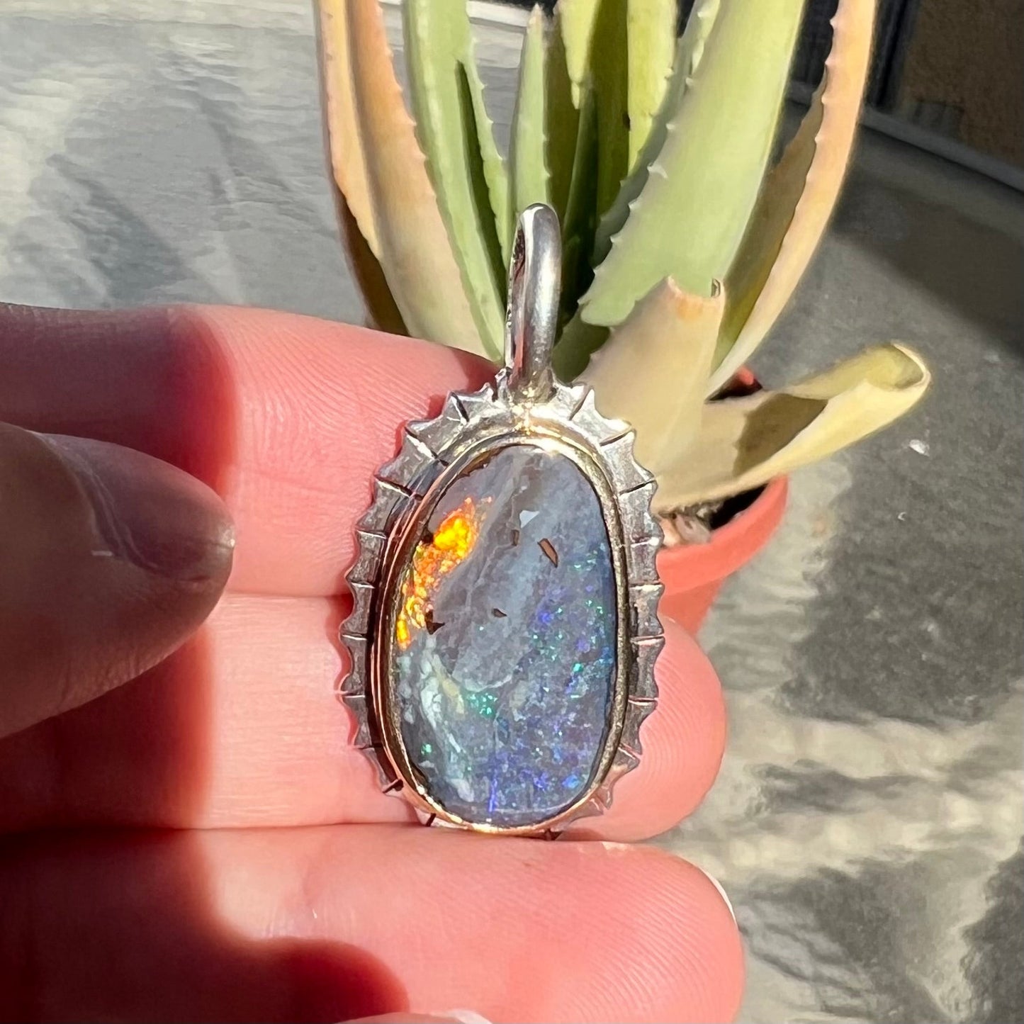 A Southwest style two-tone sterling silver pendant set with a black boulder opal with a yellow gold bezel.