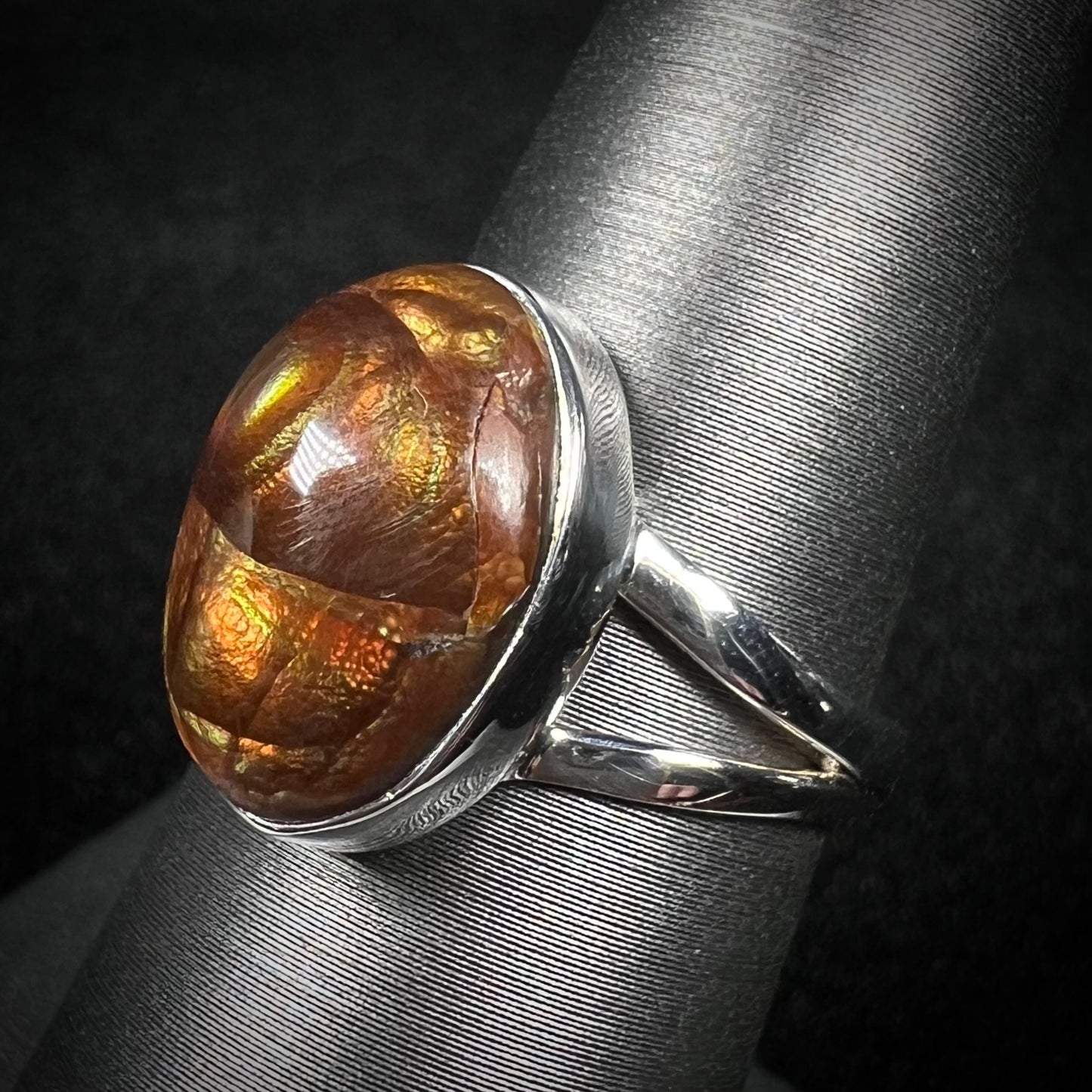 Split shank fire agate ring shown from an angled view against dark backdrop. Fire agate shows crack inclusion.