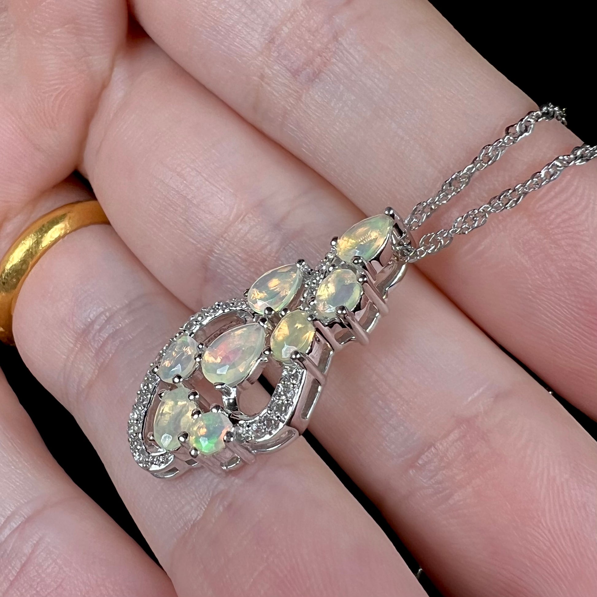 A sterling silver Ethiopian fire opal necklace, shown at an angle in a hand.
