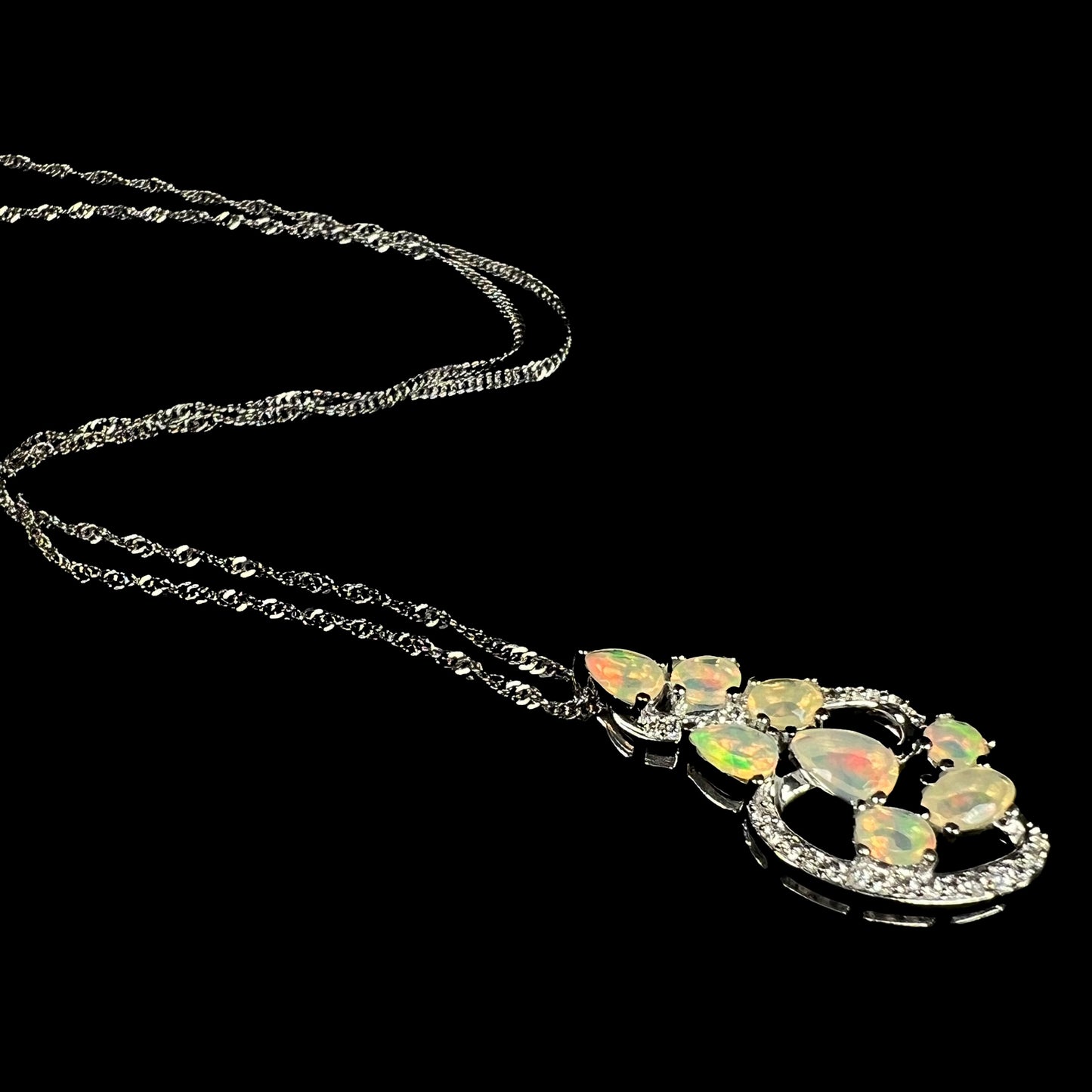 A sterling silver Ethiopian opal necklace, shown at an angle, laying on a black background.