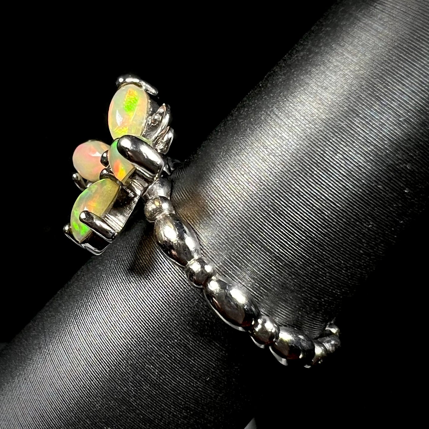 Side view of a sterling silver Ethiopian opal butterfly ring, shown on a ring display. The shank has a rounded design.