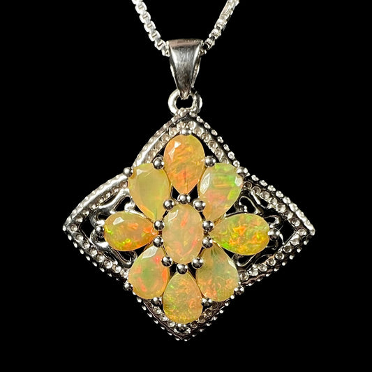 A sterling silver Ethiopian opal cluster star necklace, shown on a chain from the front against a black background.