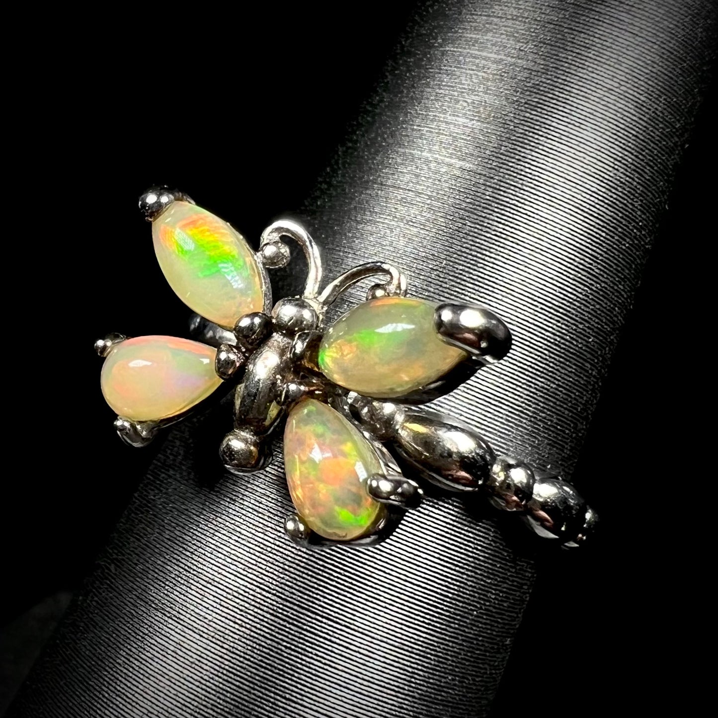 A sterling silver Ethiopian opal butterfly ring shown at an angle on a ring display against a black background.