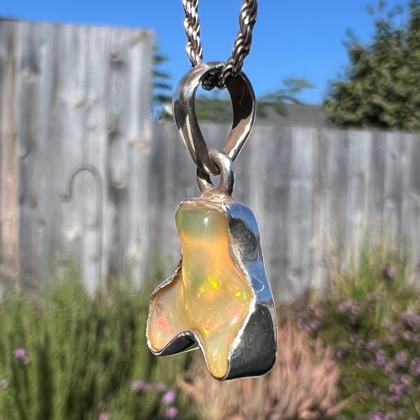 A freeform shaped Mexican fire opal necklace on a sterling silver rope chain.