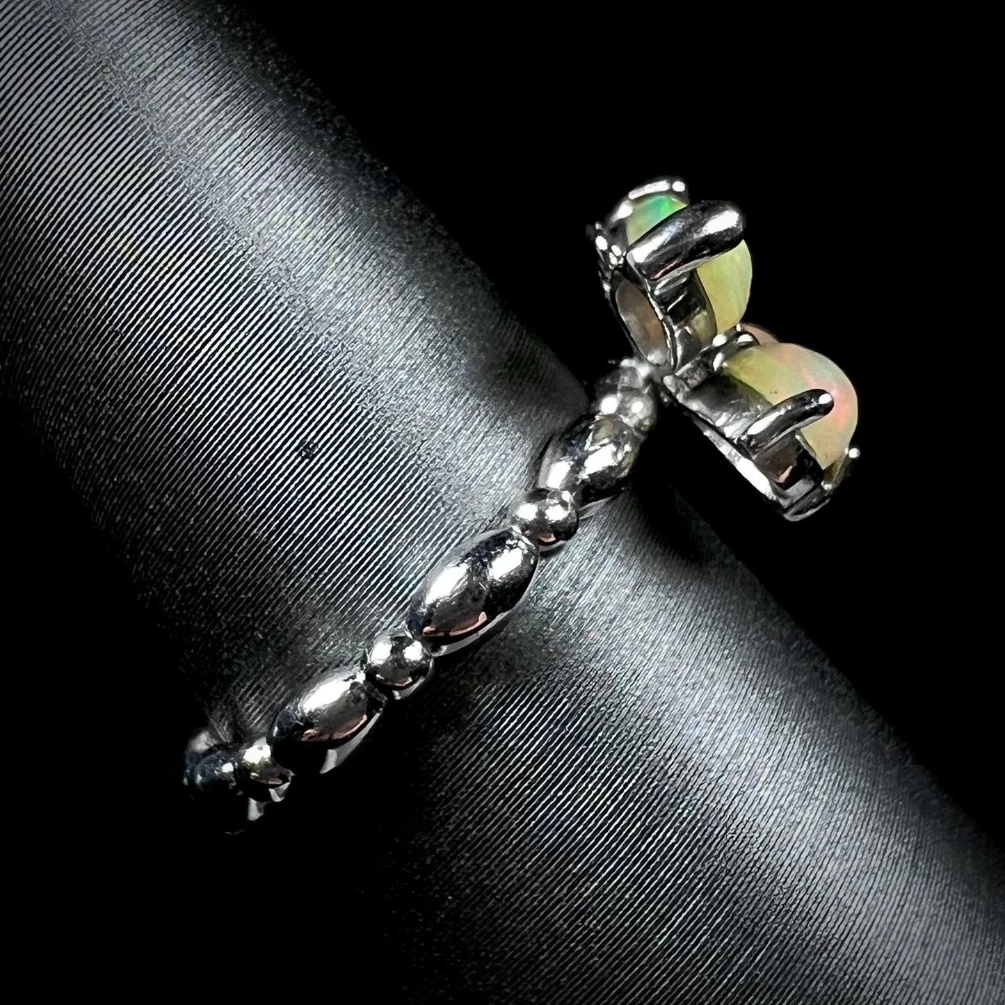 Side view of a sterling silver Ethiopian opal butterfly ring with a unique, rounded shank, shown on a ring display.