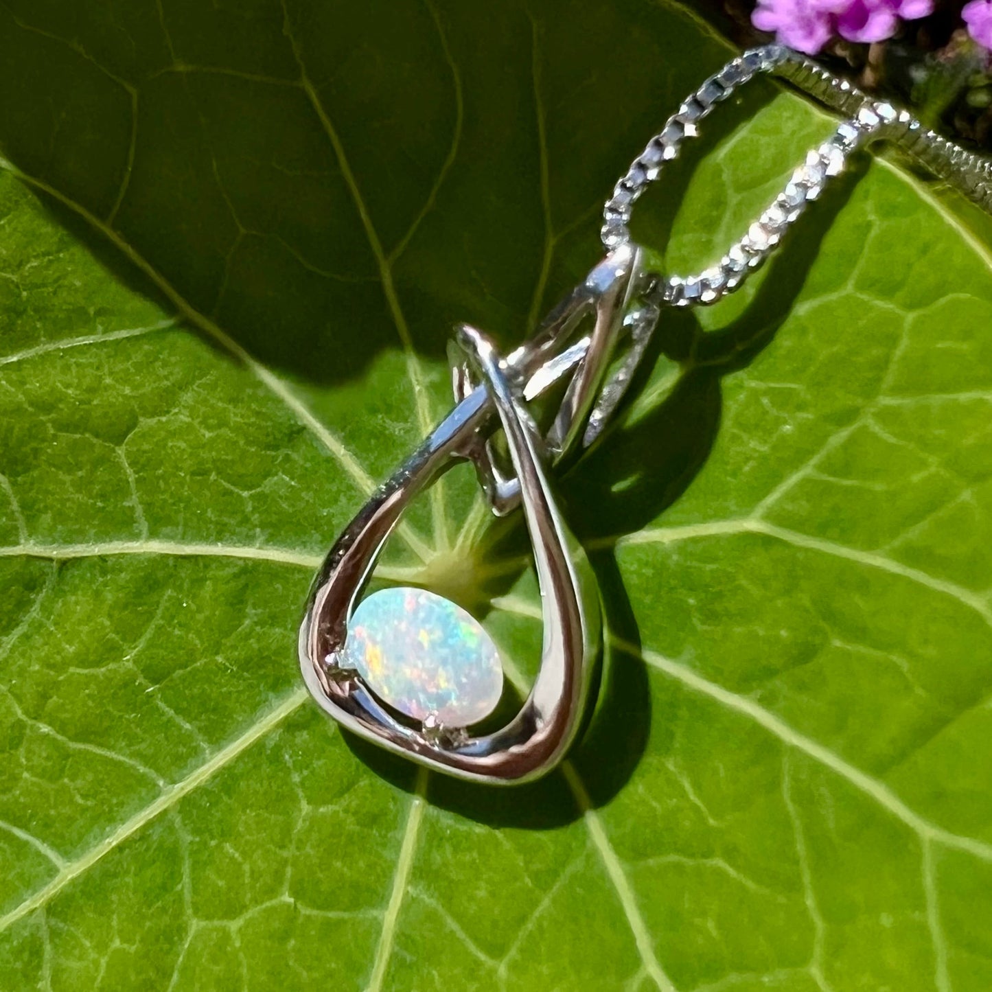 A ladies' sterling silver pendant set with an oval cabochon cut natural white crystal opal.