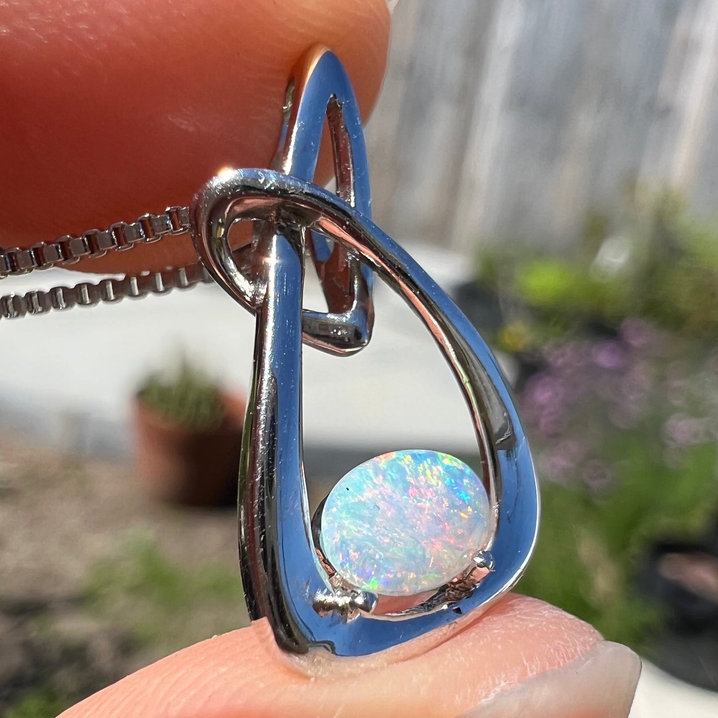 A ladies' sterling silver pendant set with an oval cabochon cut natural white crystal opal.