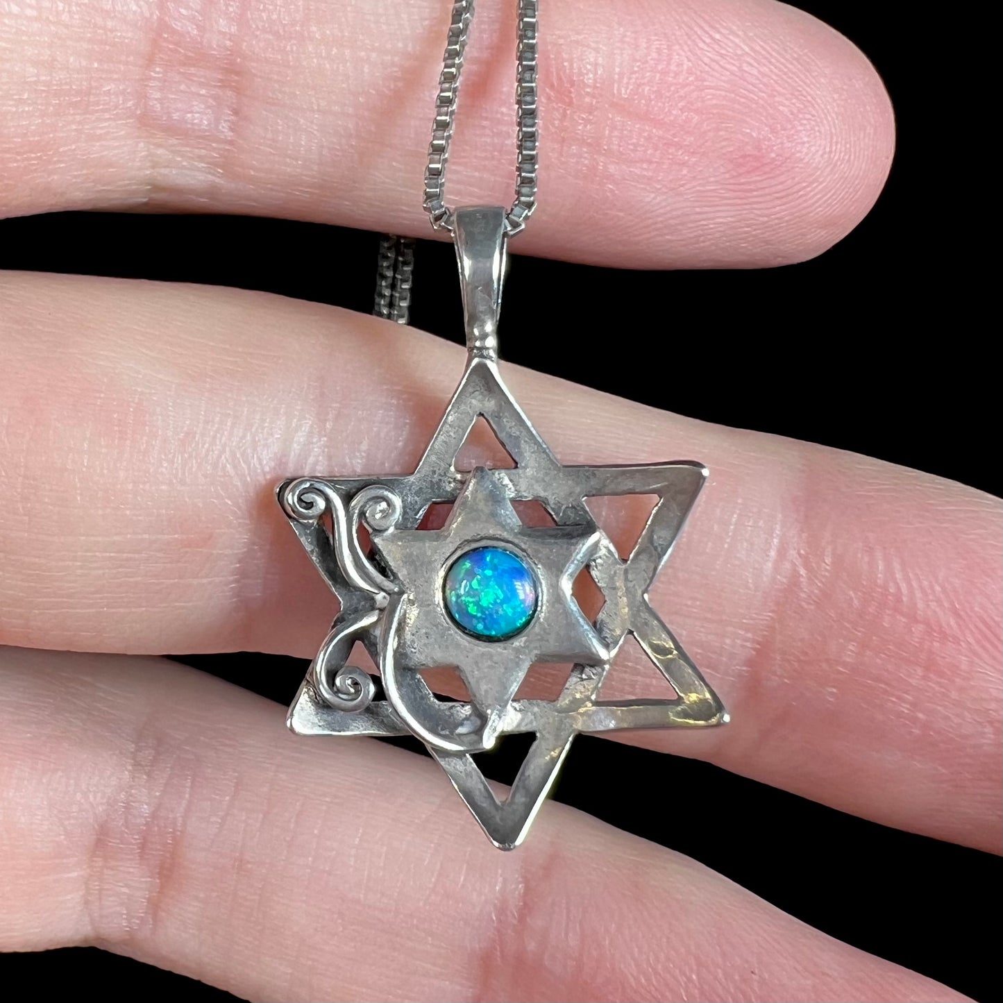 A sterling silver Star of David necklace set with a round blue lab-created opal.