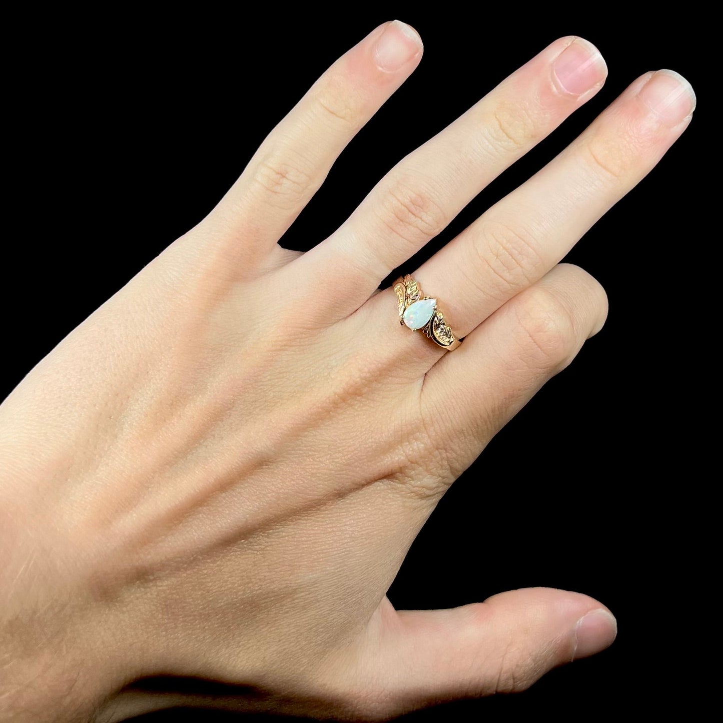 A ladies' two-tone yellow and rose Black Hills gold opal and diamond ring. The opal is a pear shaped cabochon.
