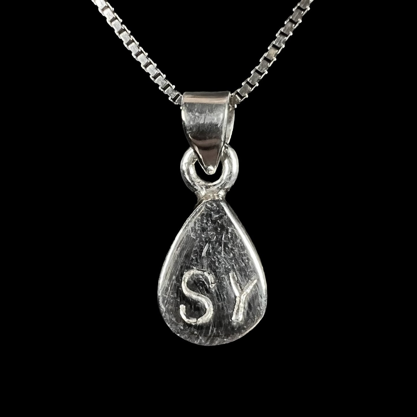 A dainty, sterling silver necklace bezel set with a natural, pear shaped opal stone.