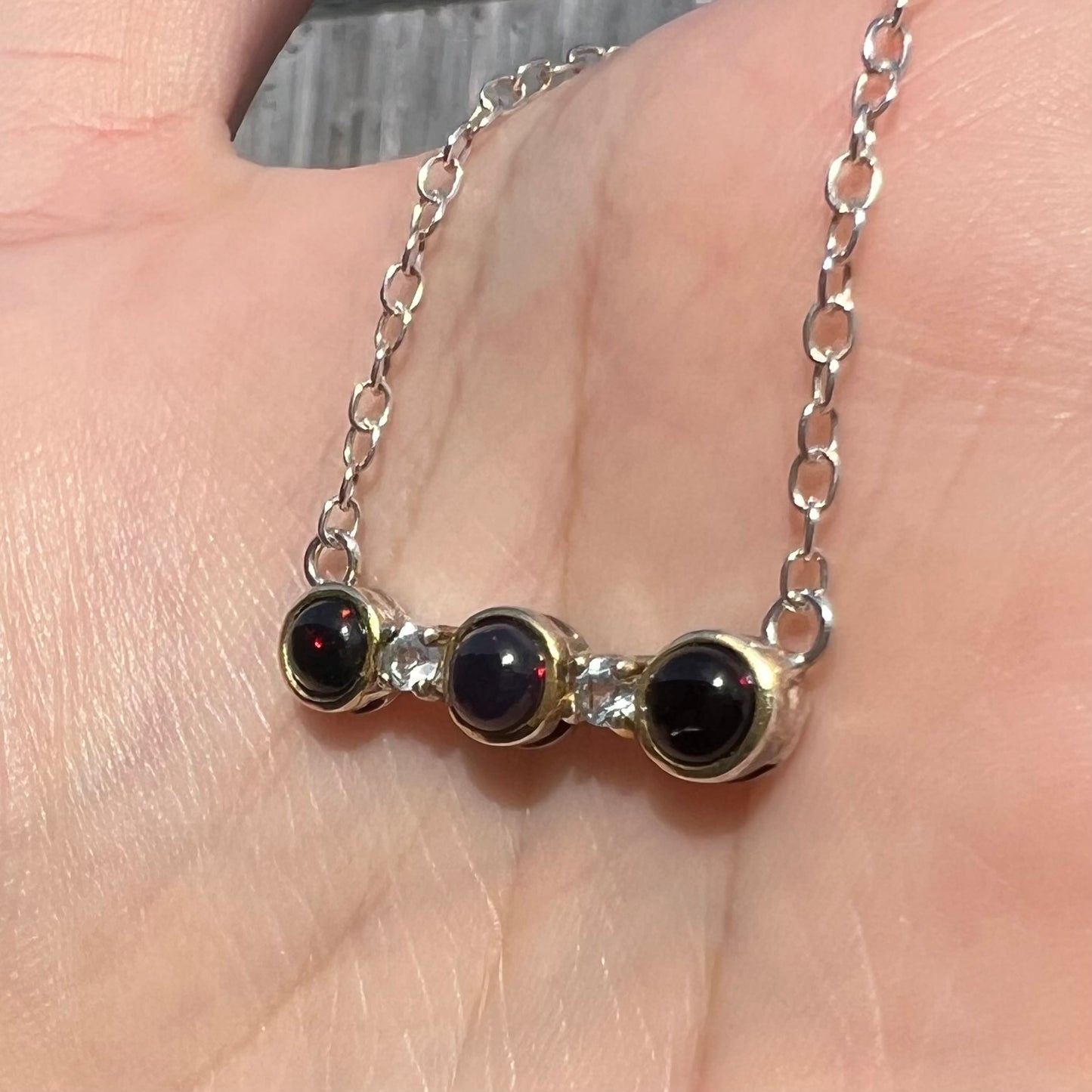A three-stone black Ethiopian opal and white topaz necklace in two-tone sterling silver.